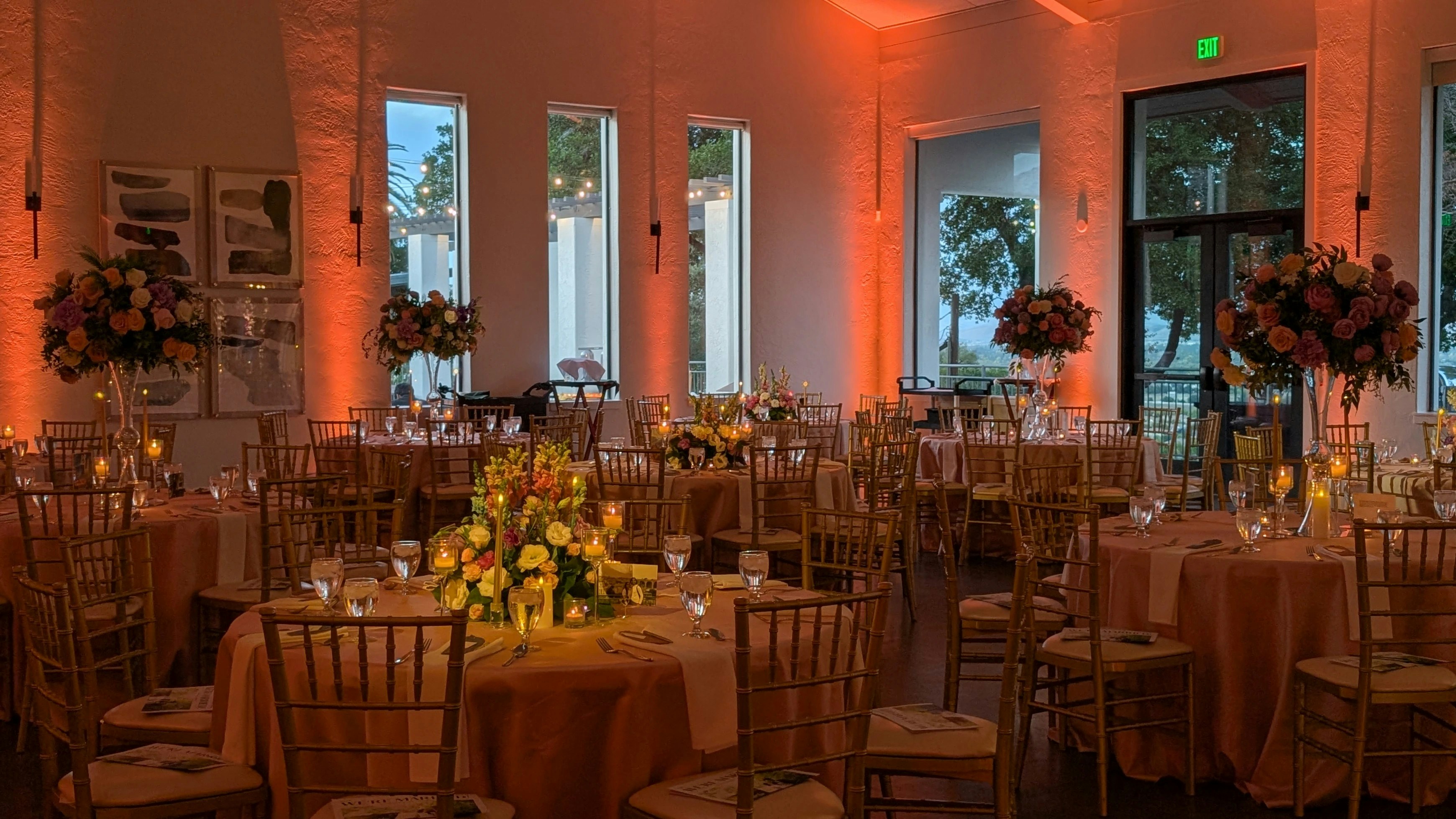 Eleganter Veranstaltungsraum mit floralen Mittelstücken und warmem orangefarbenem Licht.