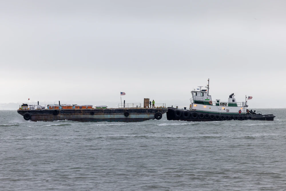 Tugboat pushing a large barge across open water