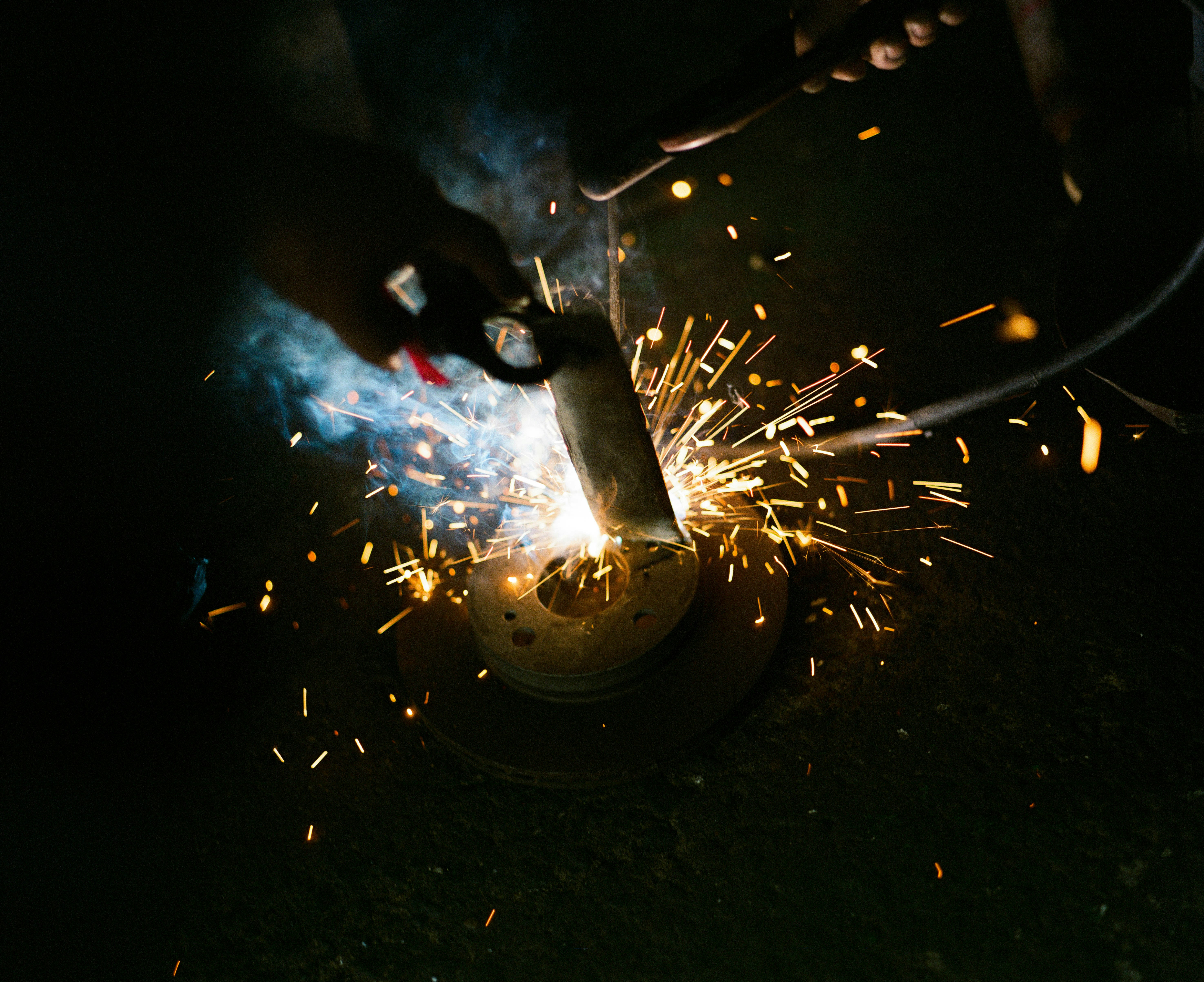 Welding sparks illuminate a dark workshop