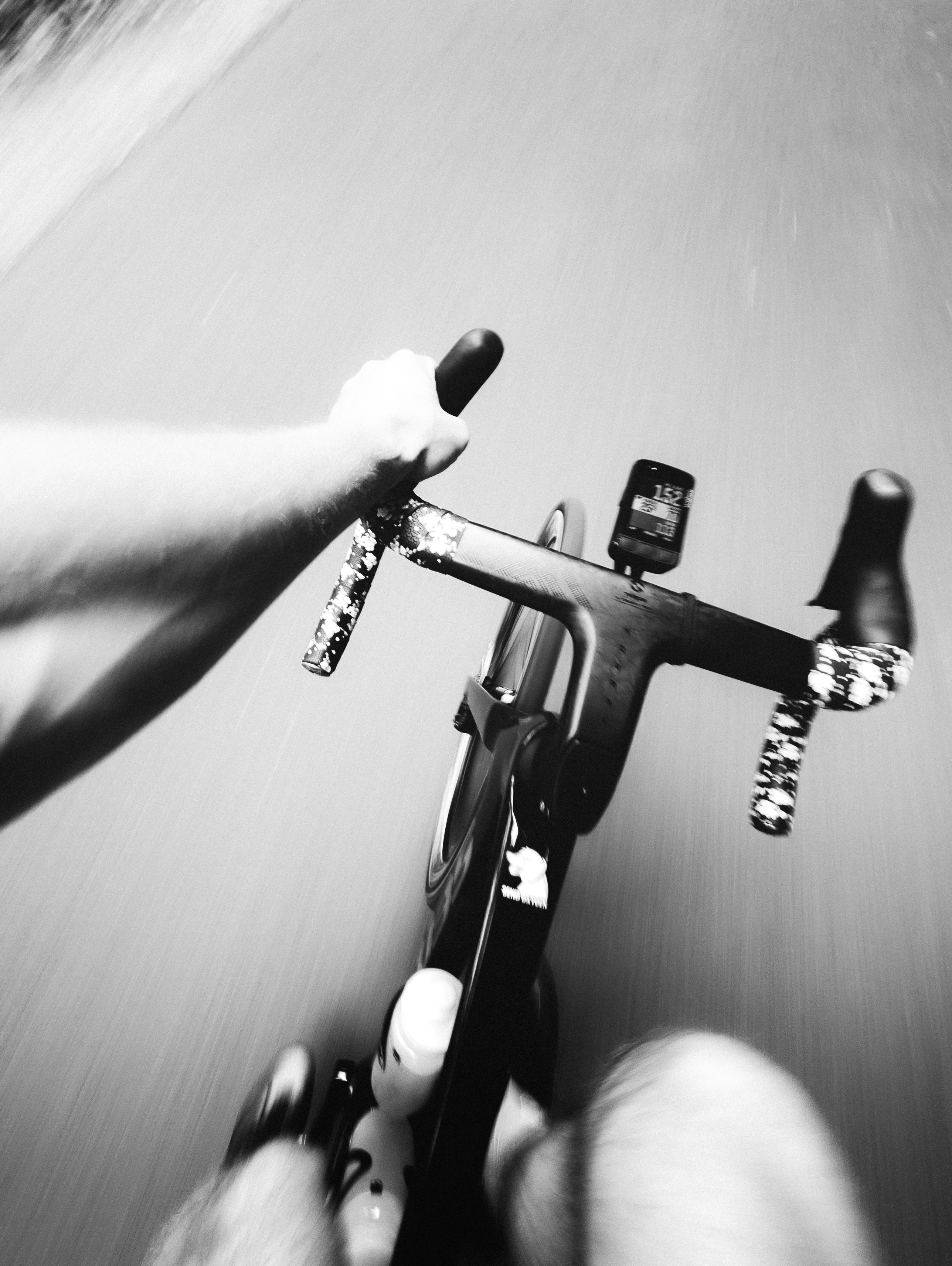 Black and white view of a person cycling rapidly.
