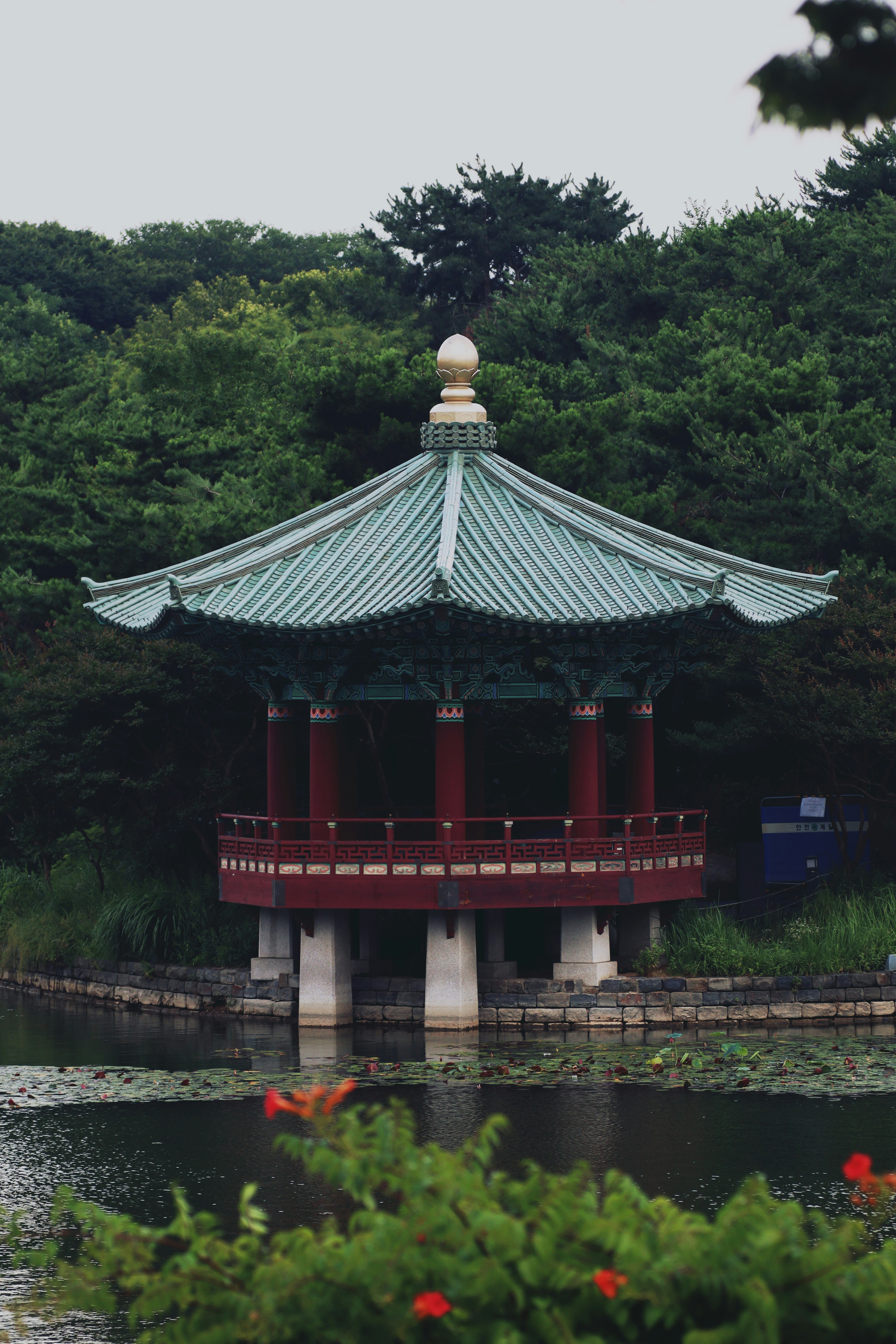 Traditional korean pavilion with green roof by a tranquil lake.