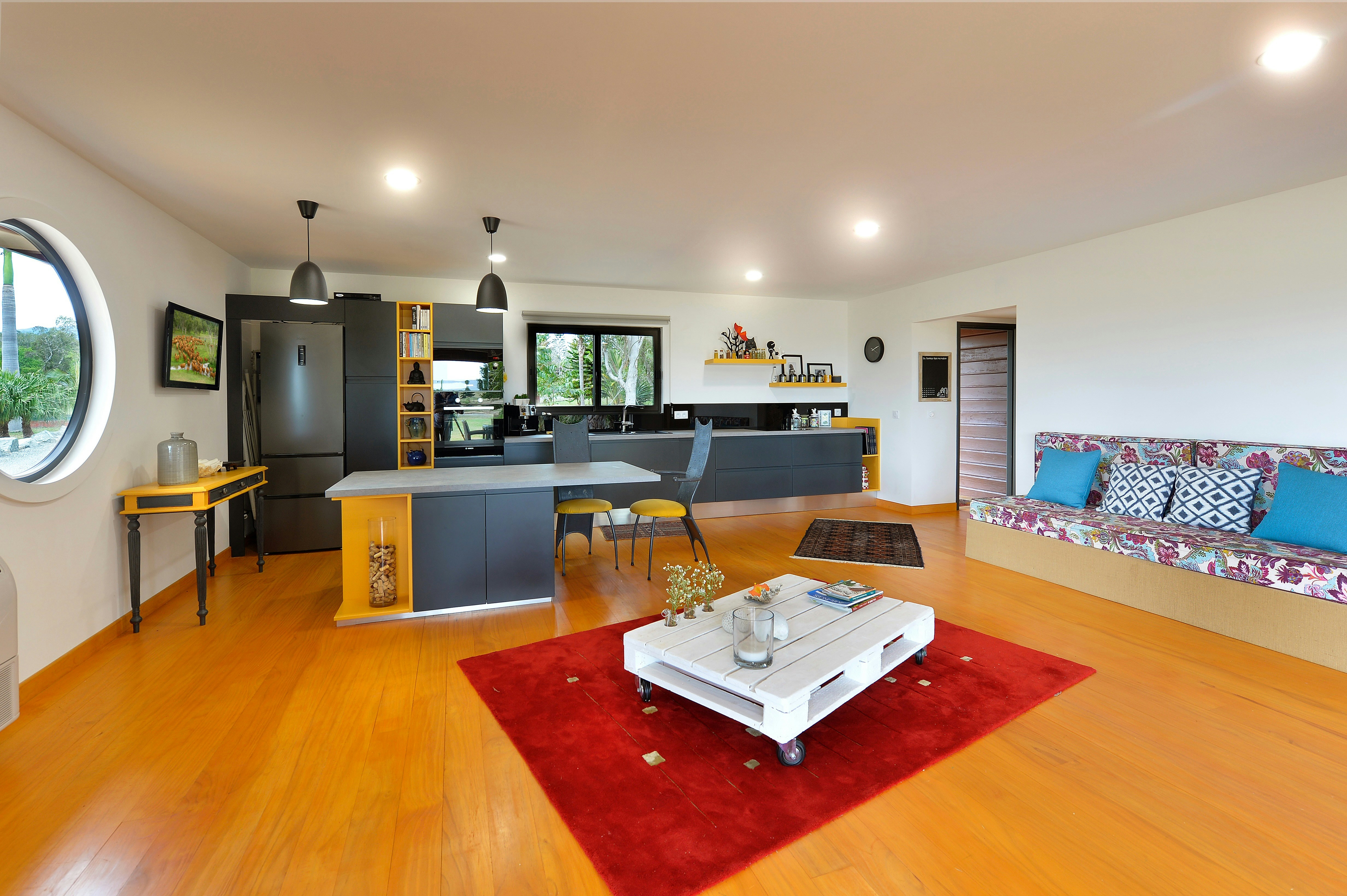 Sala de estar e cozinha modernas em planta aberta com piso de madeira.