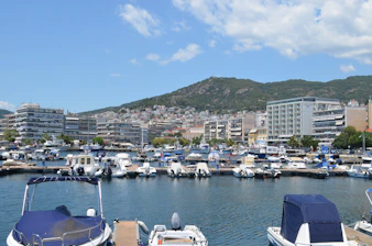 Boats moored in a marina with a city and mountains