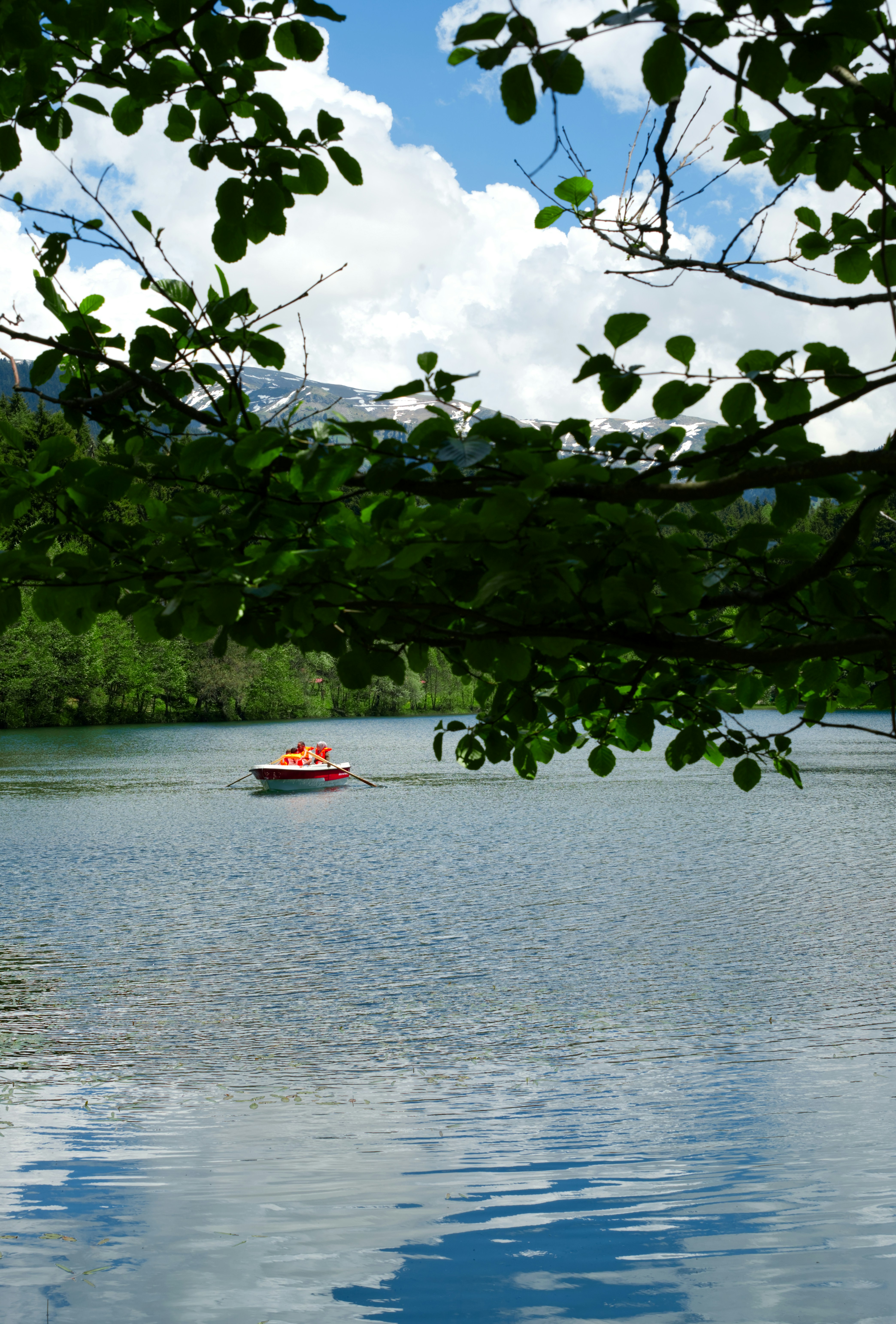 Zwei Personen paddeln mit einem kleinen Boot auf einem ruhigen See.