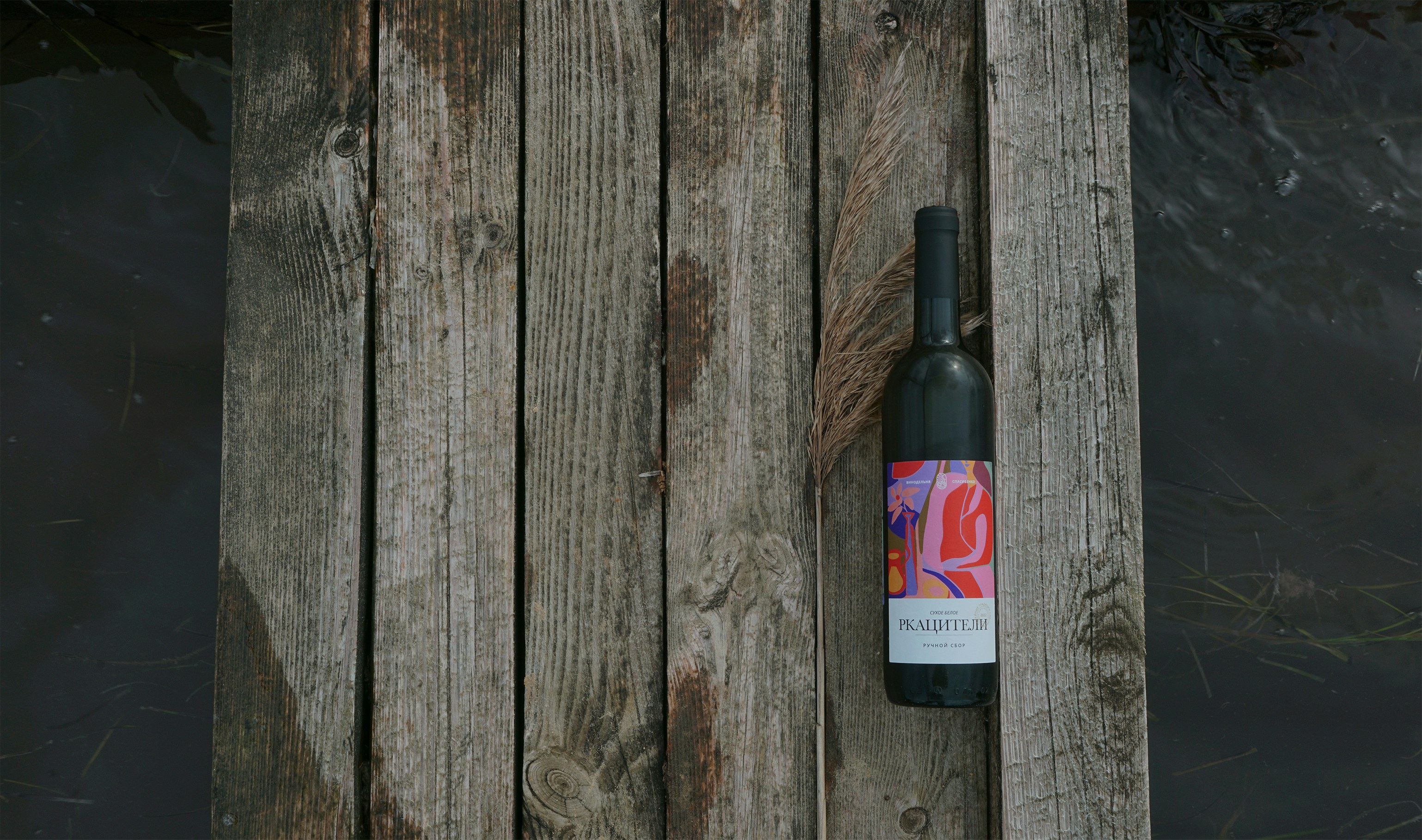 Wine bottle with colorful label on a wooden dock.
