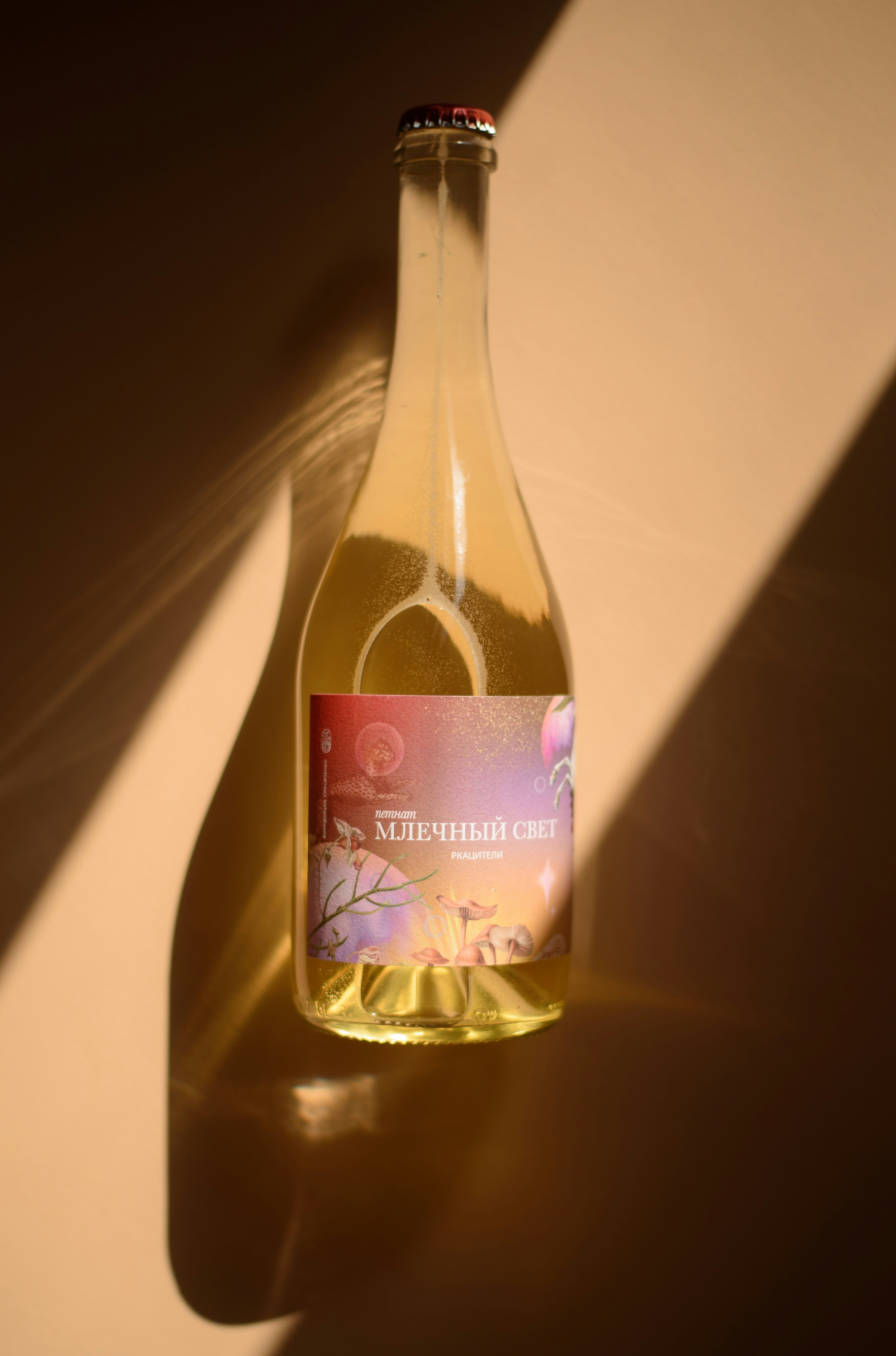 Clear glass bottle with colorful label and strong shadows.