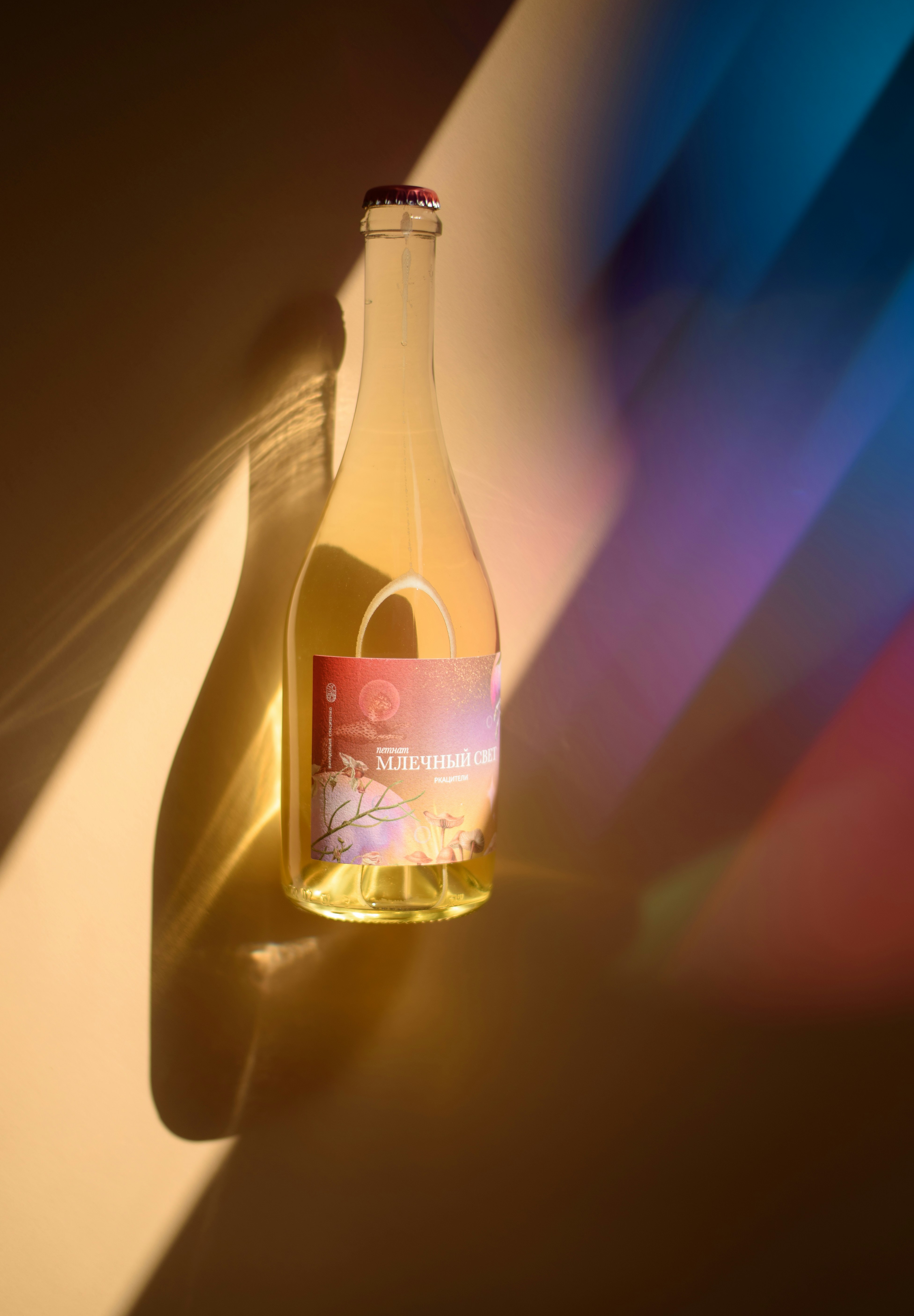 A bottle of sparkling beverage with colorful light and shadows.