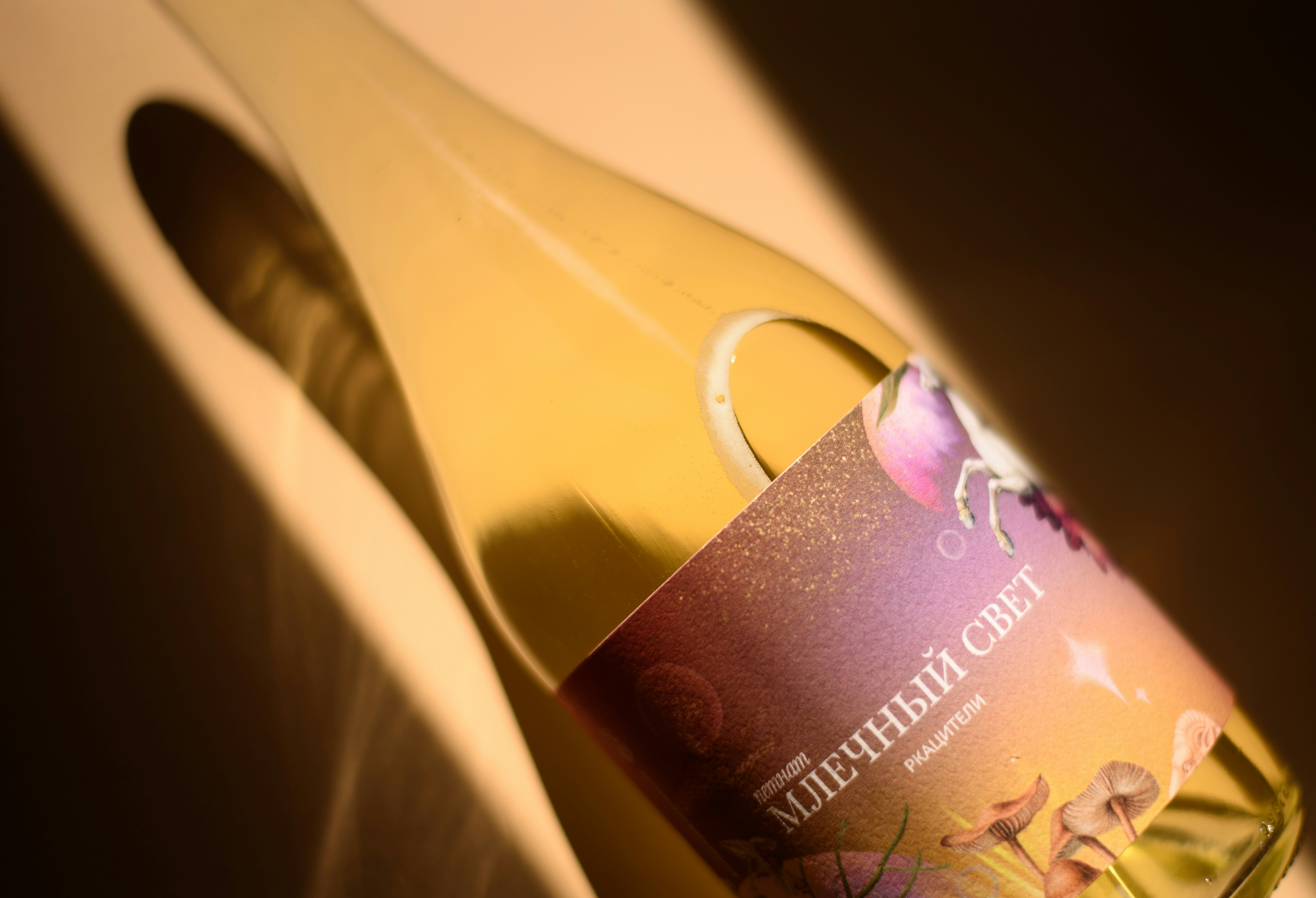 White wine bottle with a colorful label and strong shadow.