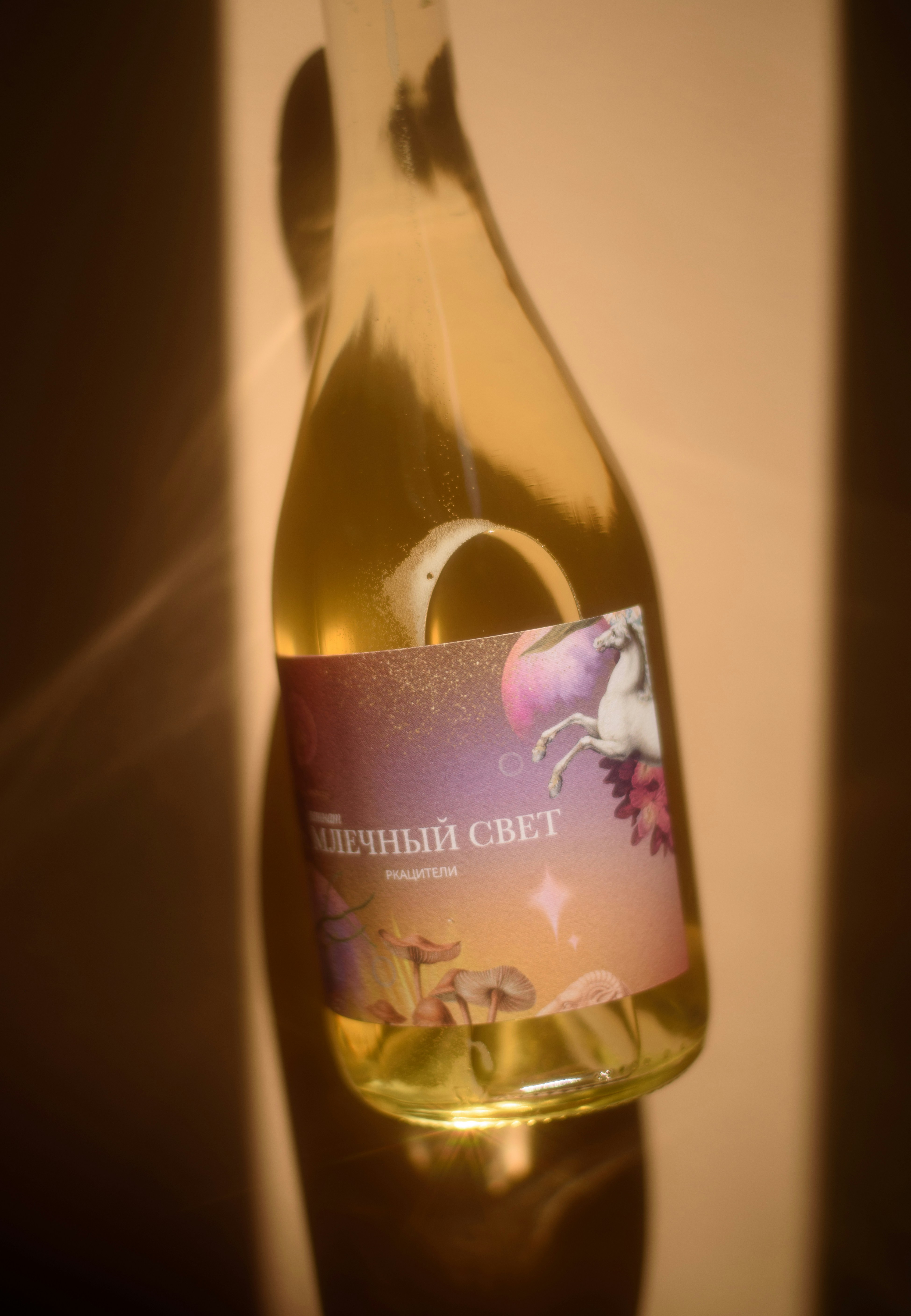Bottle of white wine with a unicorn label in sunlight.