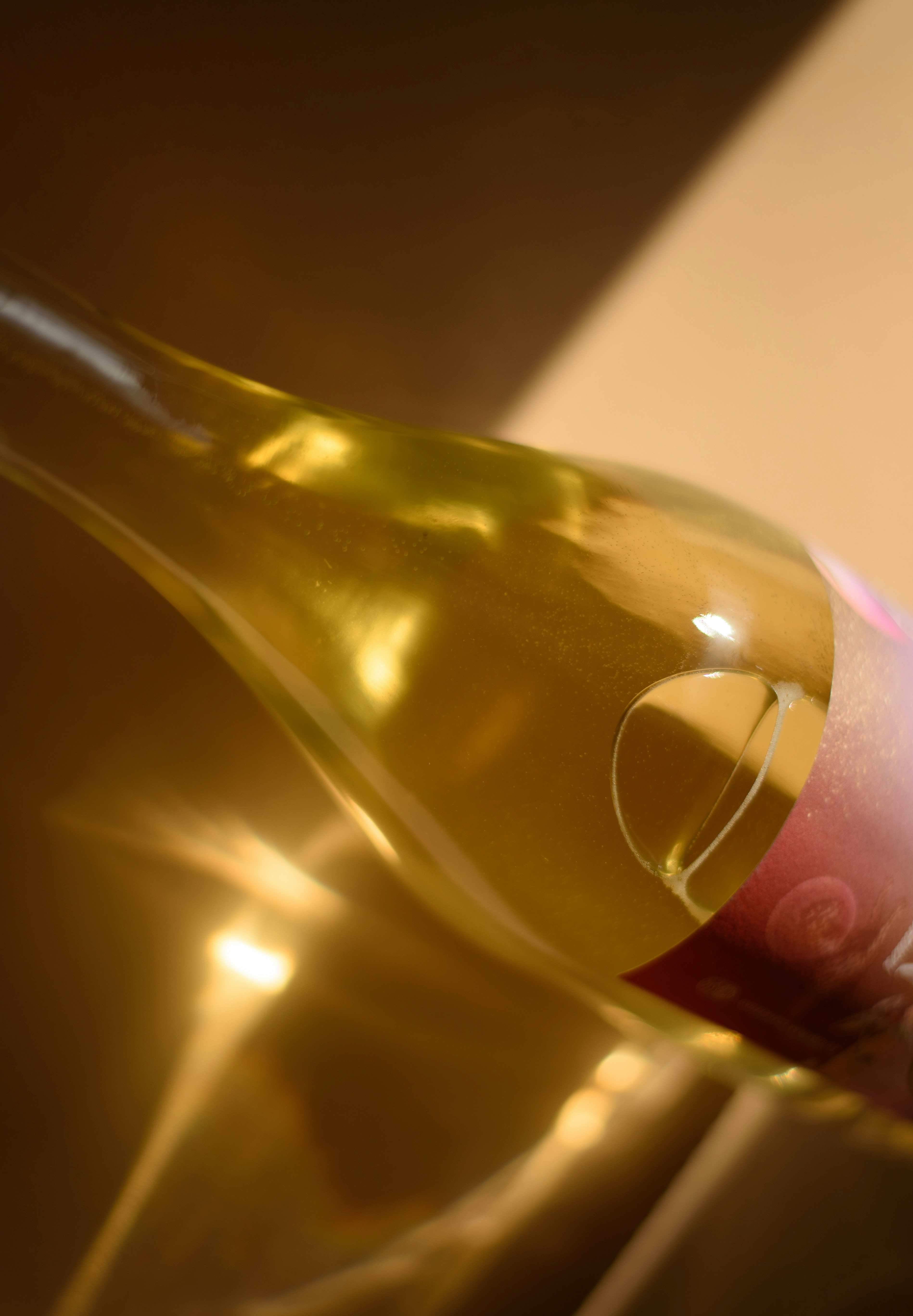 Wine bottle with golden liquid and a pink label.