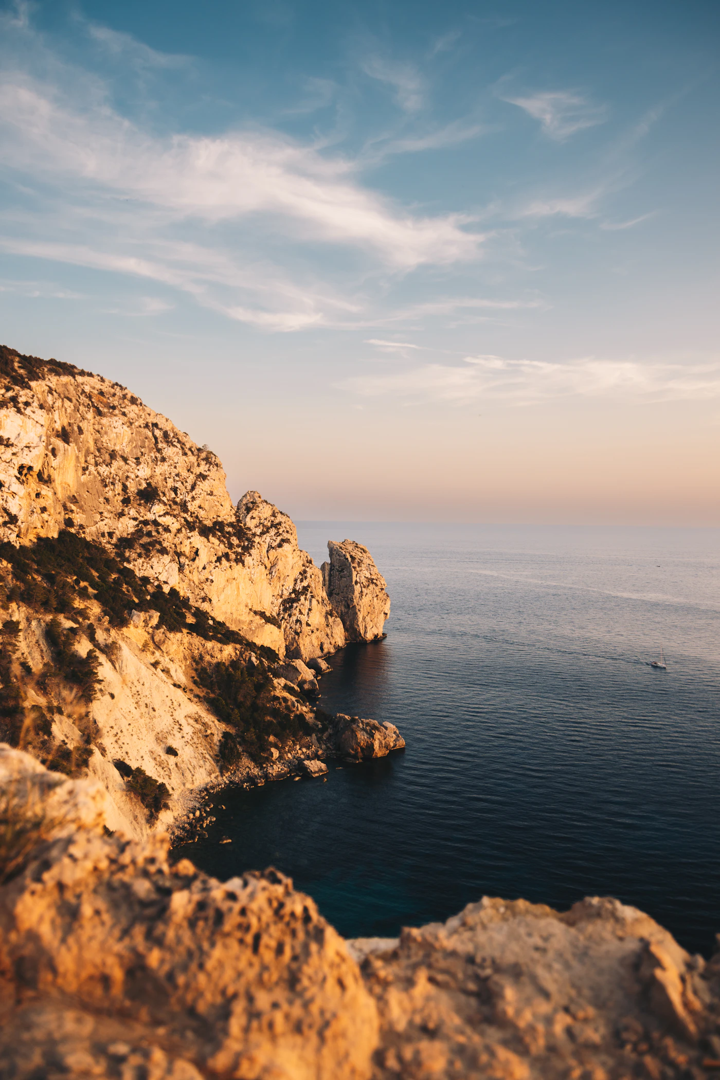 Golden light on Mediterranean sea cliffs above a calm blue sea
