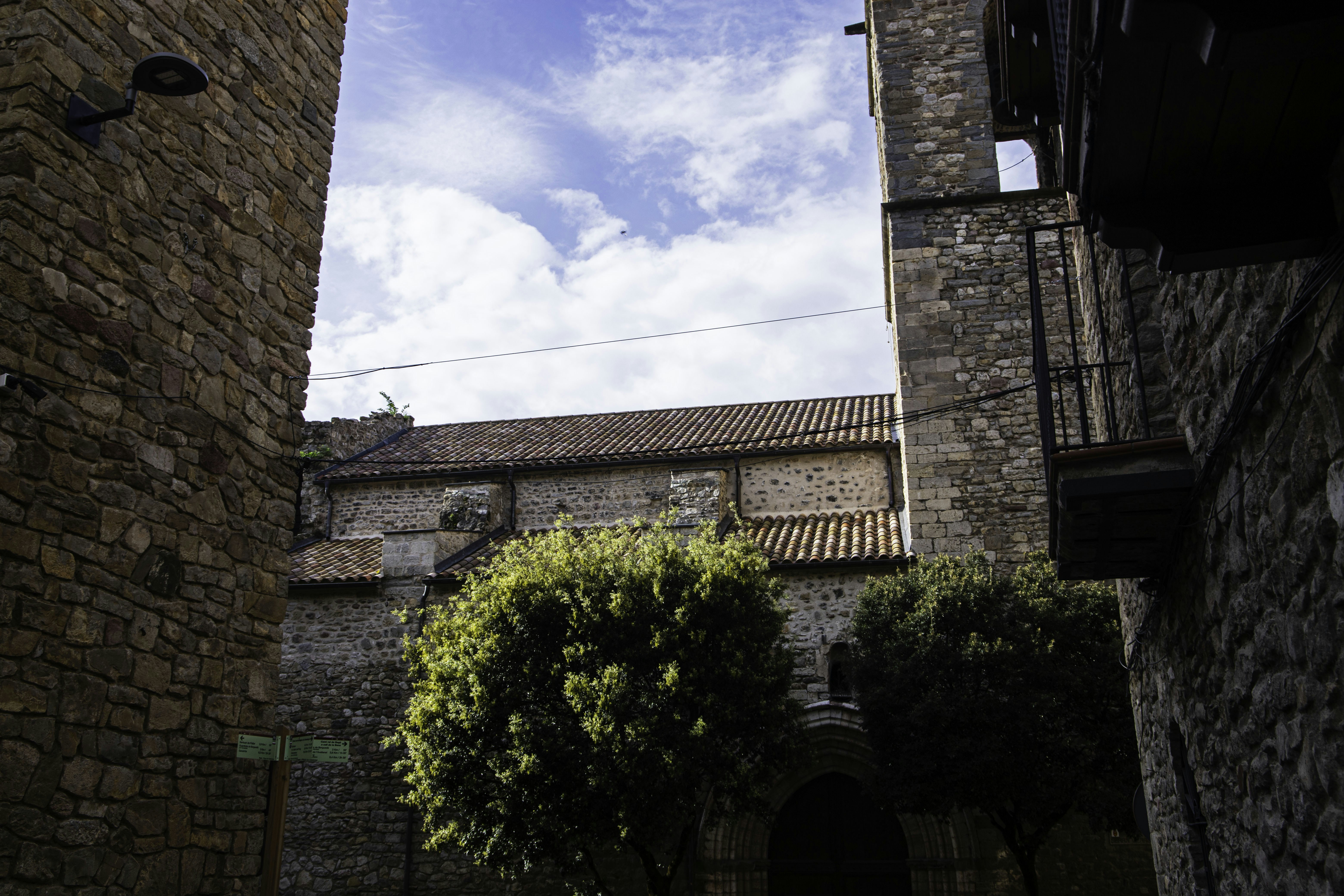 Ancient stone buildings with green trees under a cloudy sky.