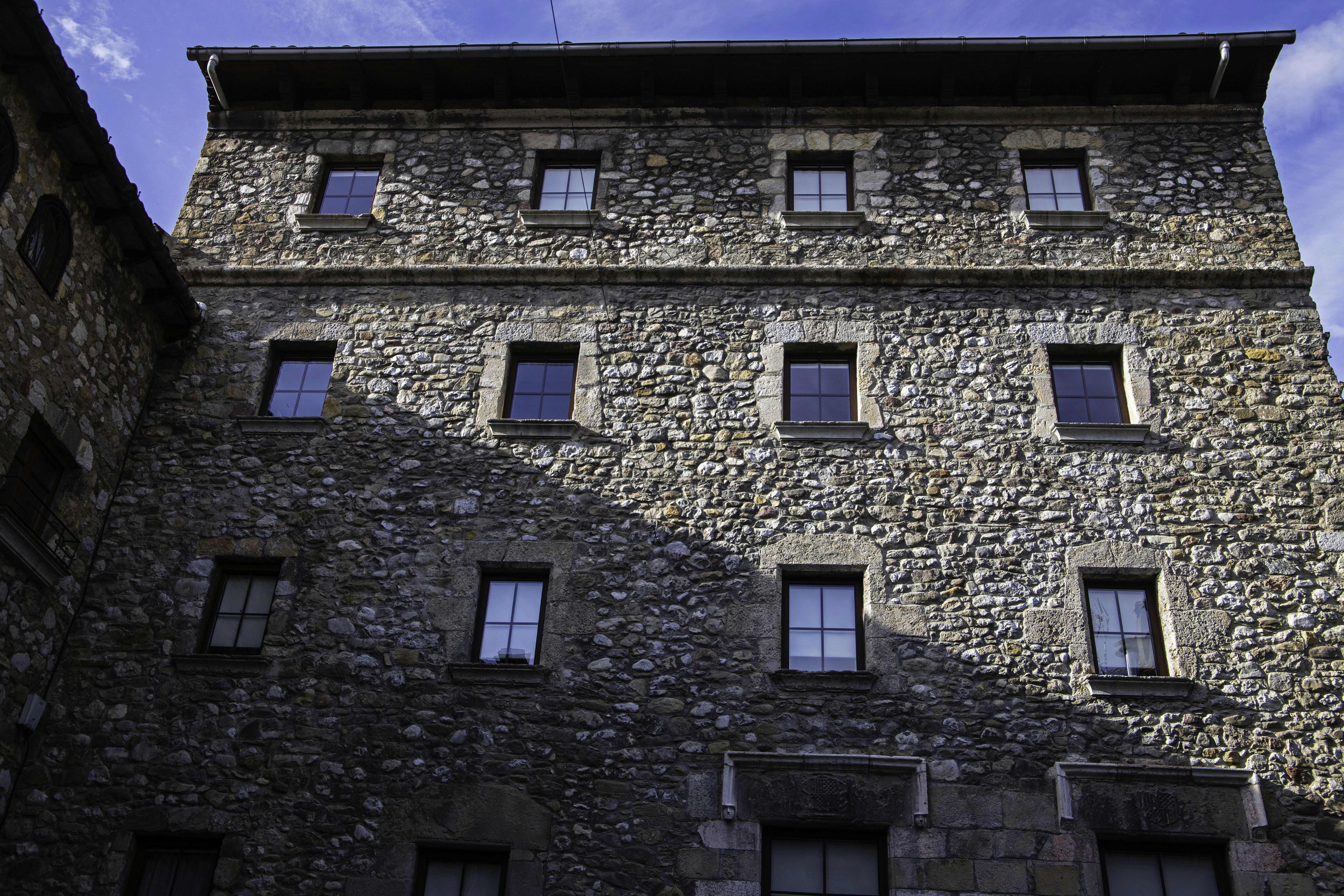 A stone building with many windows under a blue sky.
