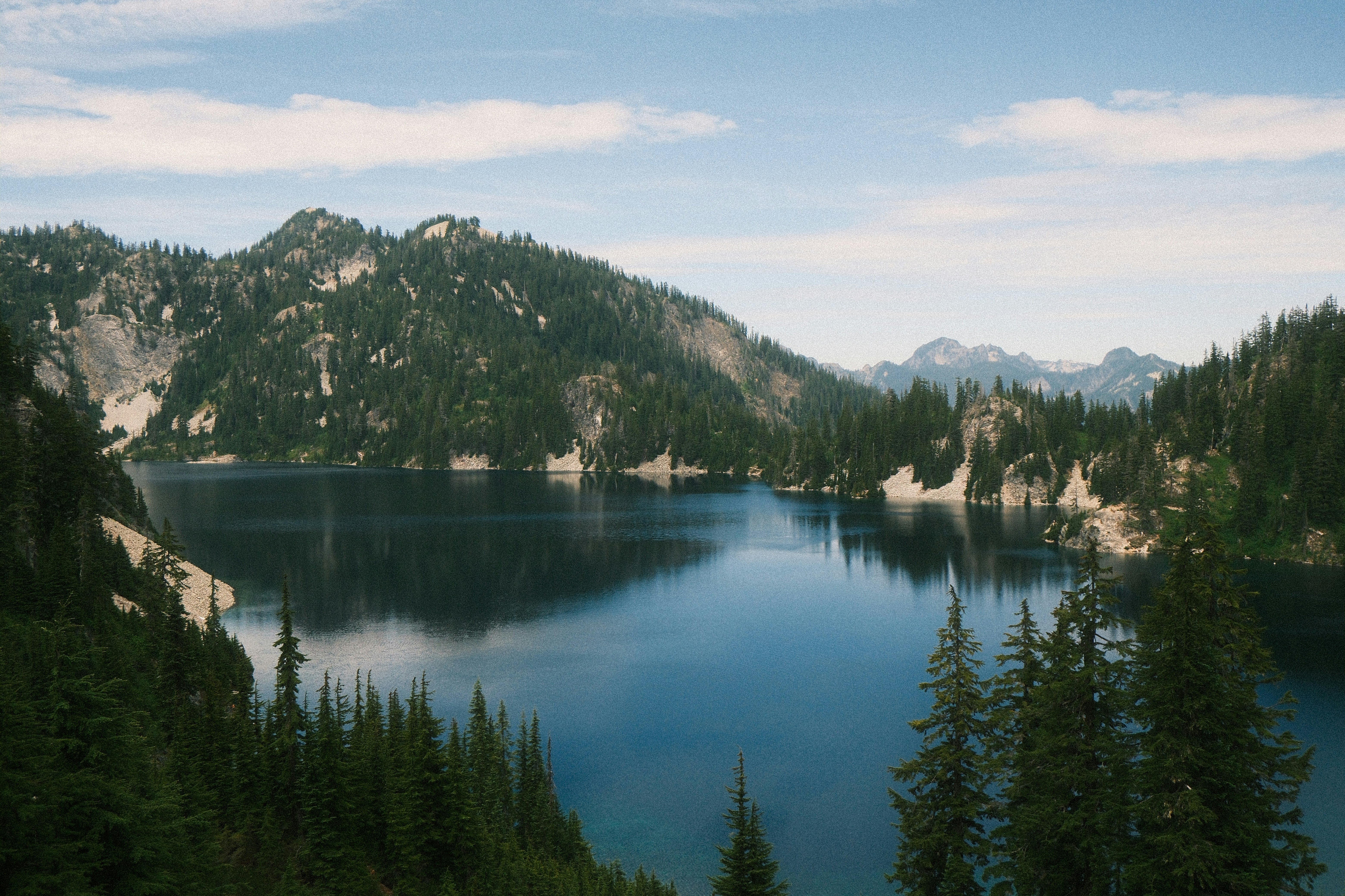 A serene blue mountain lake surrounded by evergreen forests.