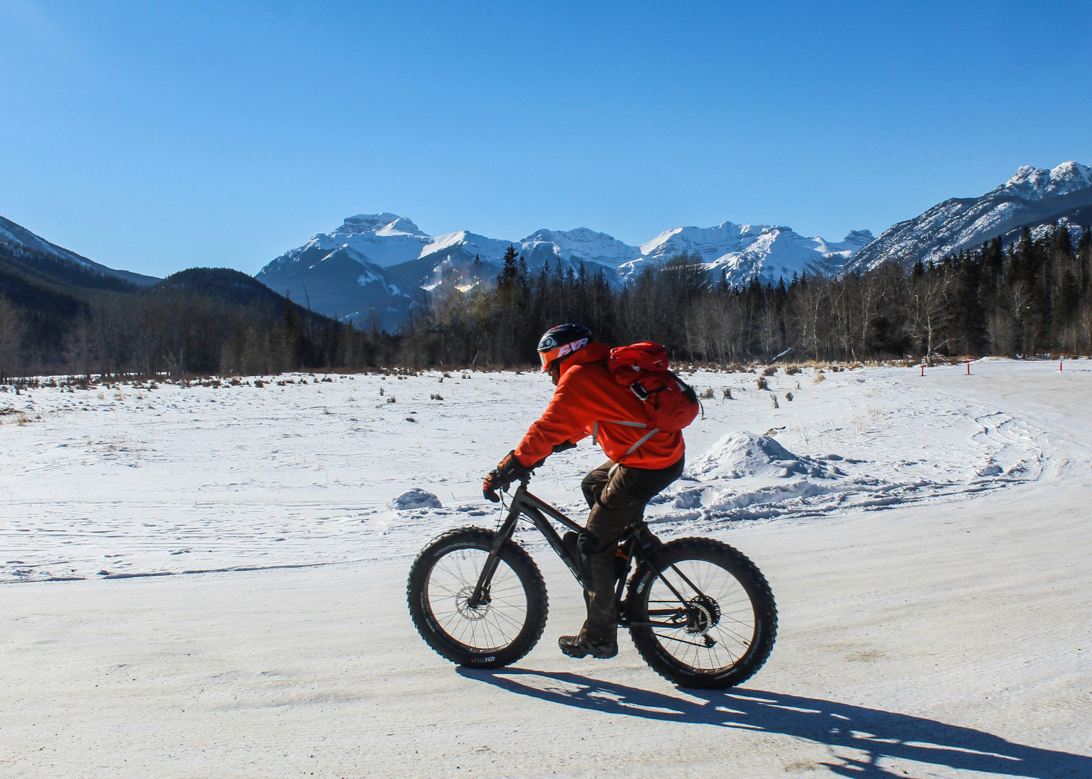A person fat biking on a snowy trail with mountains.