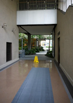 Indoor walkway with a wet floor sign and a mat.