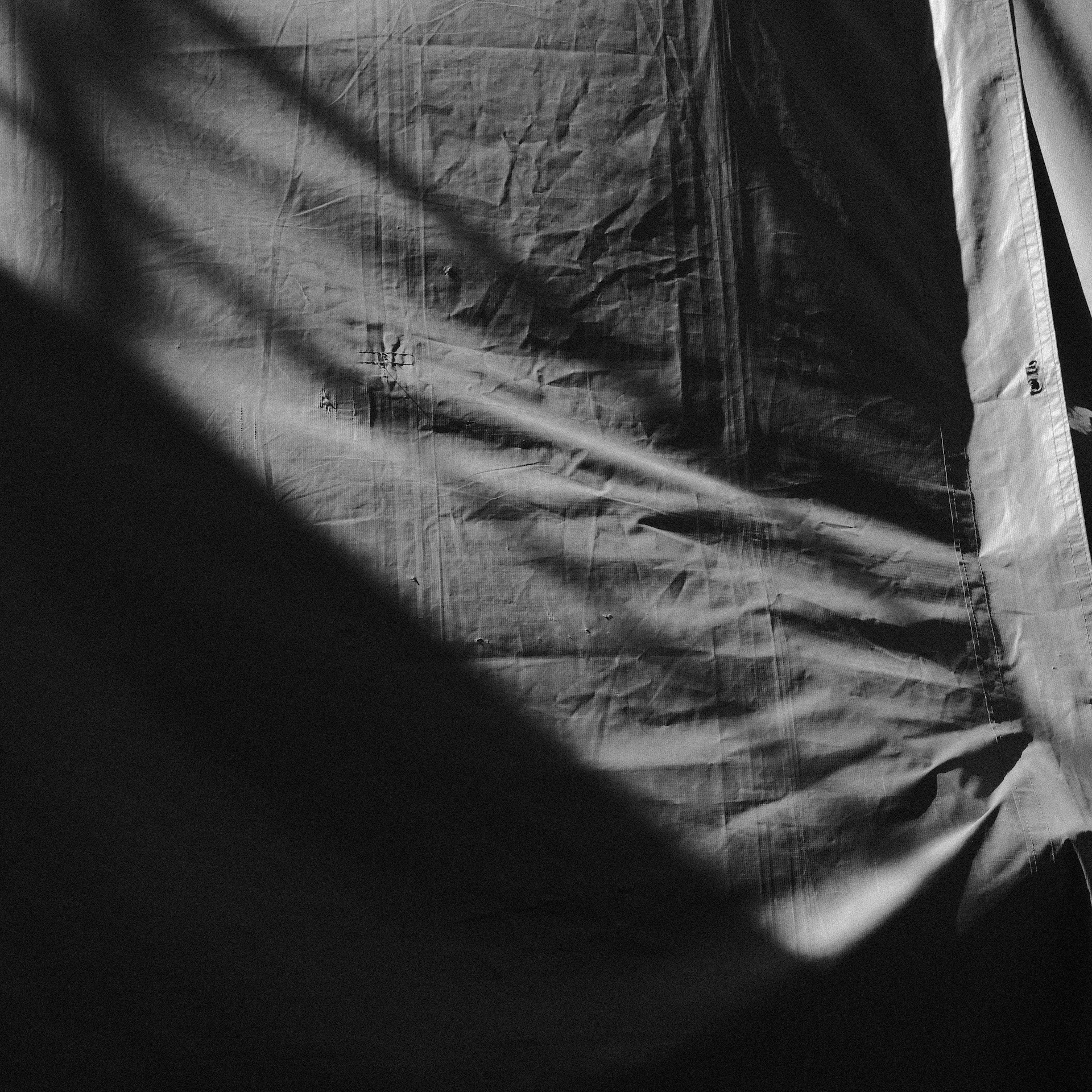 Abstract monochrome fabric with strong diagonal shadows and light
