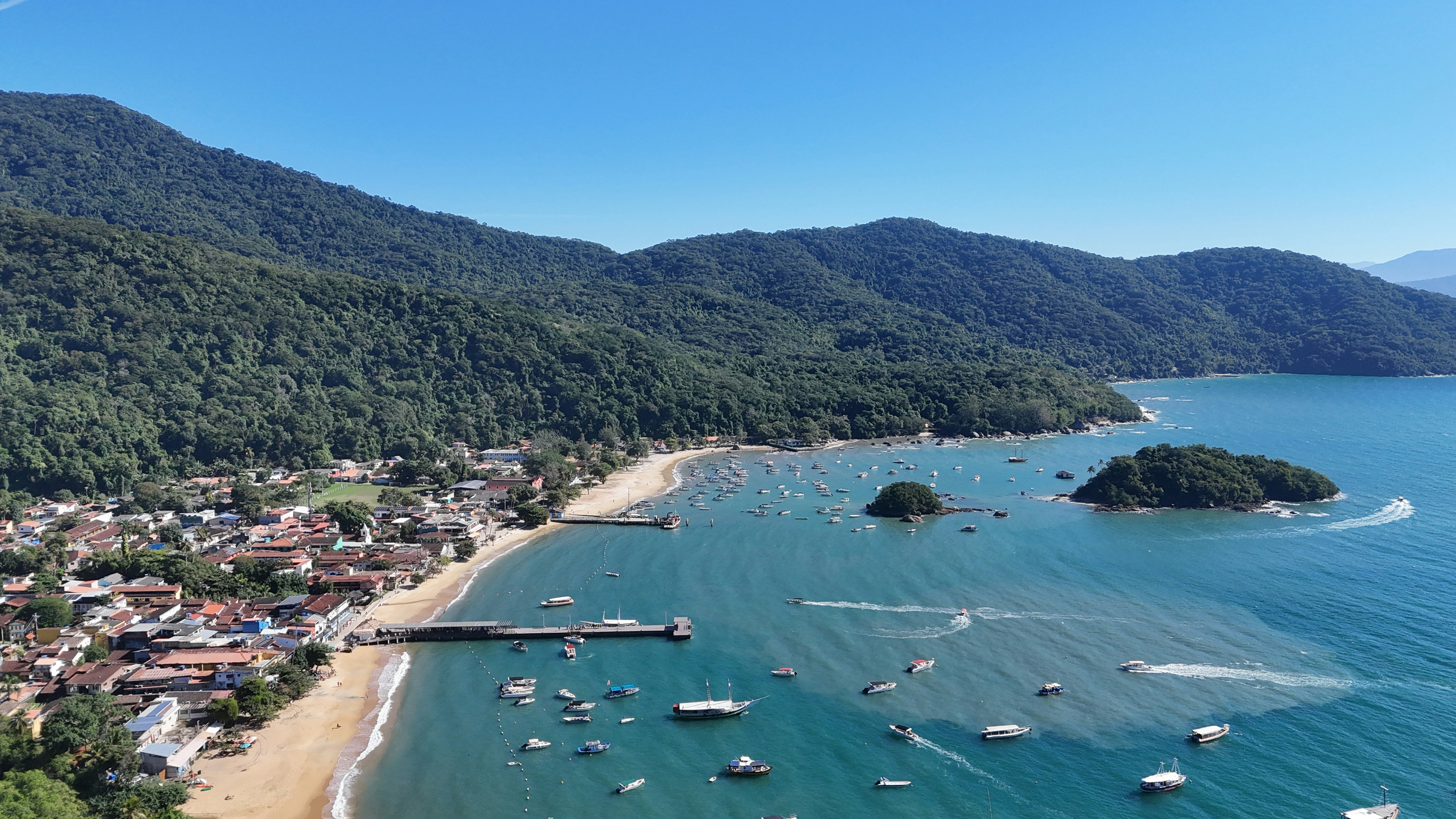 Scenic coastal town, boats in bay, and lush green mountains.