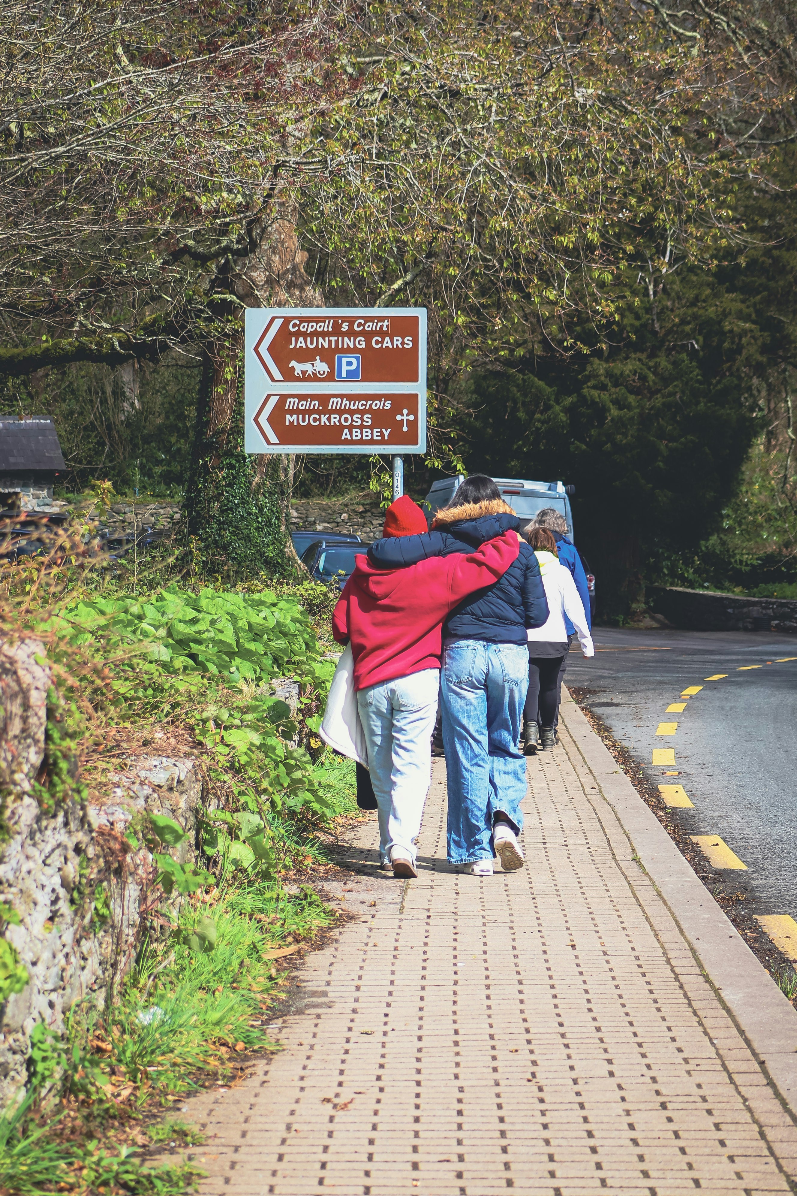 People walking on a path with a brown tourist sign.