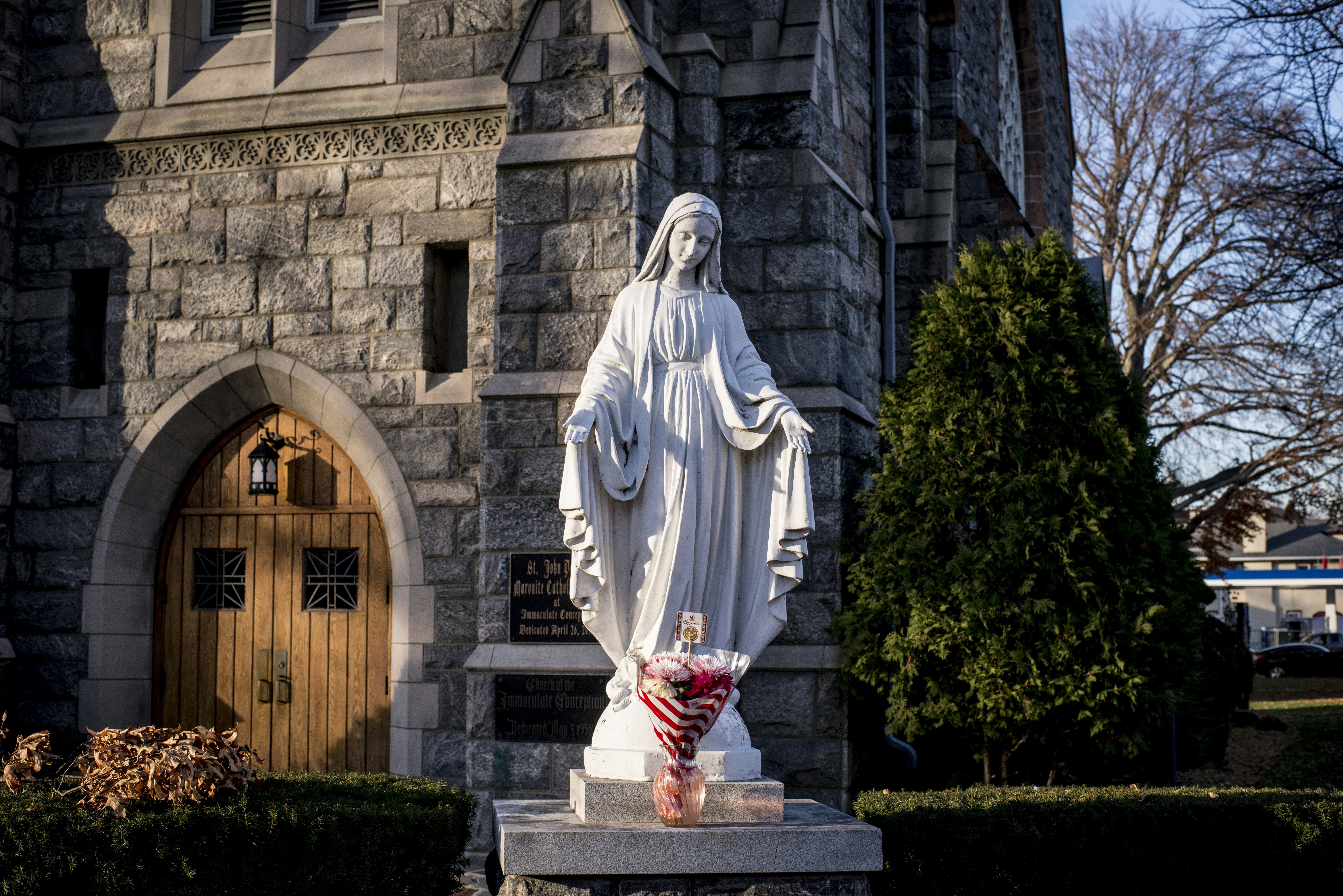 Virgin mary statue with candles before a stone church