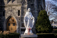 Virgin mary statue with candles before a stone church