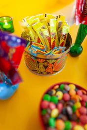 A decorative tin holds yellow candy packets and colorful candies
