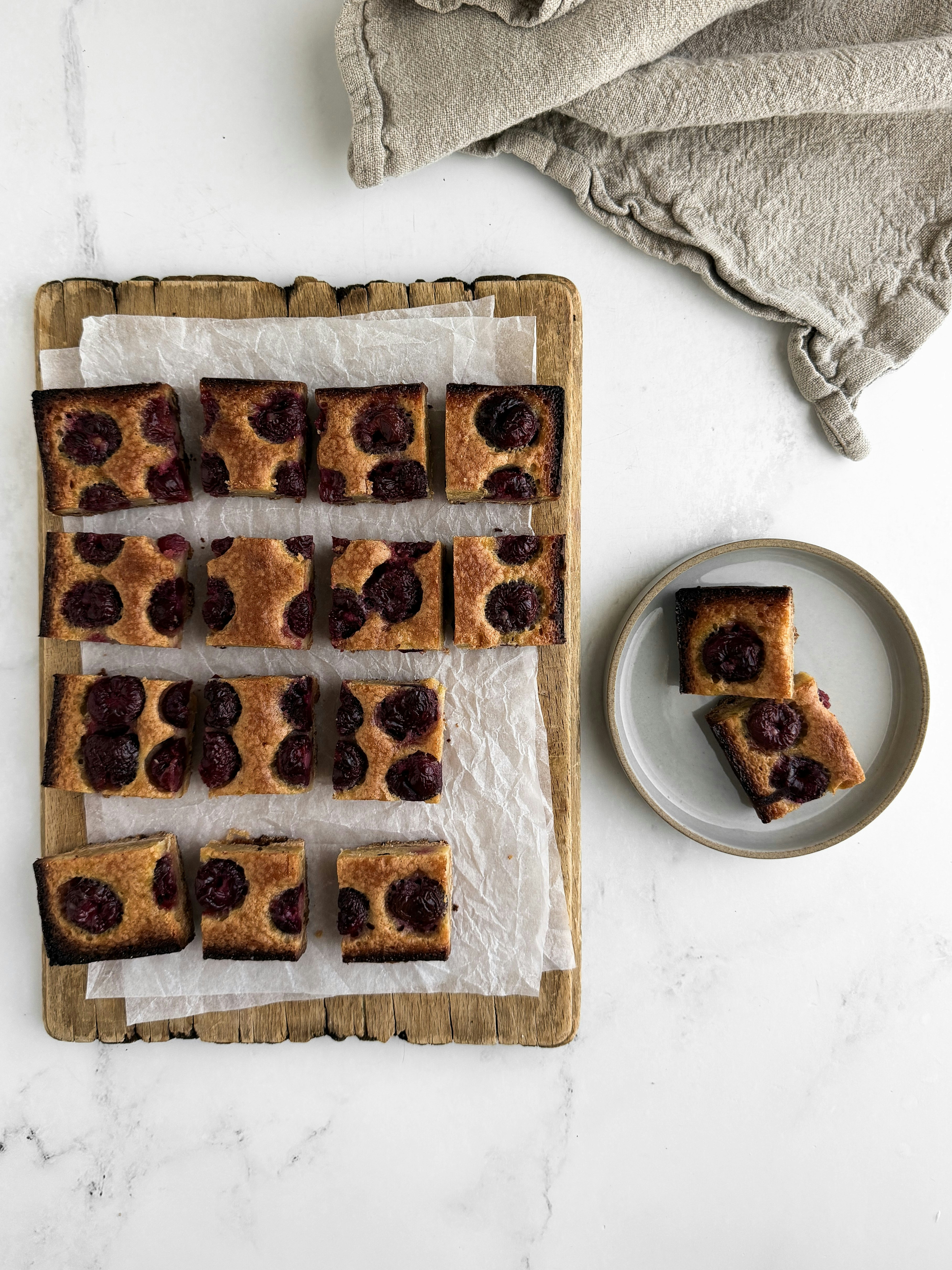 Homemade cherry cake squares on a wooden board.