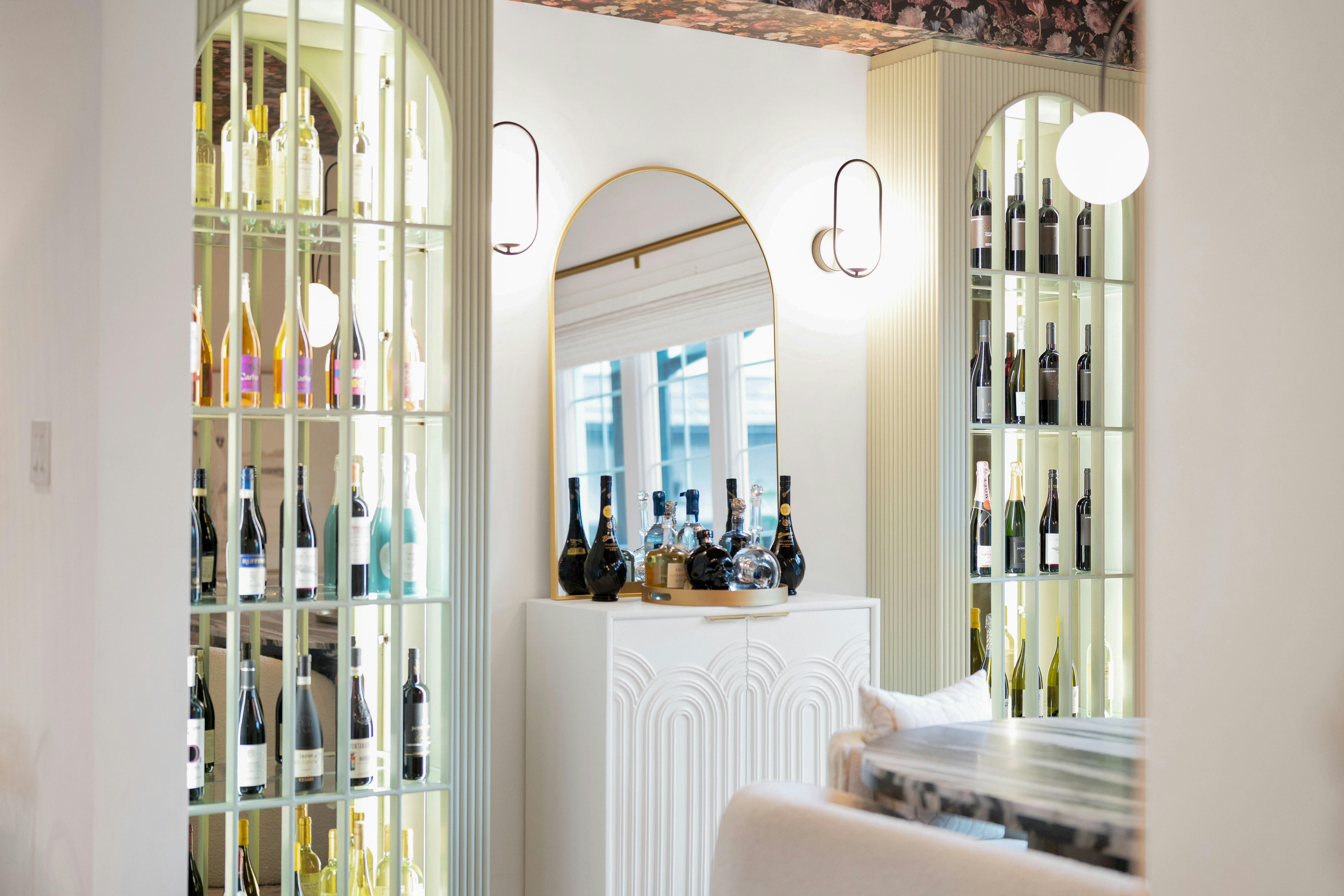 Elegant interior with arched wine displays and a central mirror.