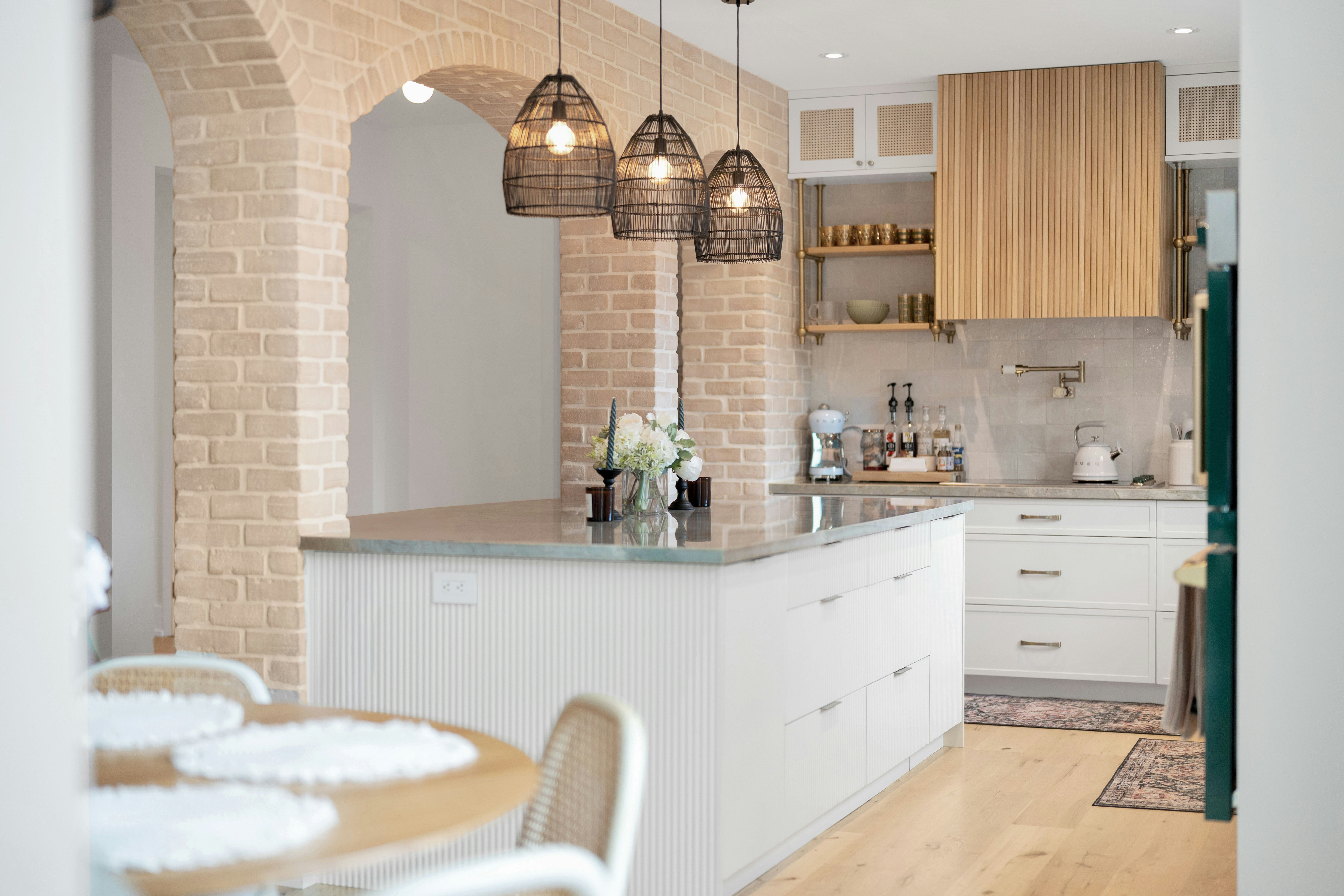 A modern kitchen with a large island and brick archways.
