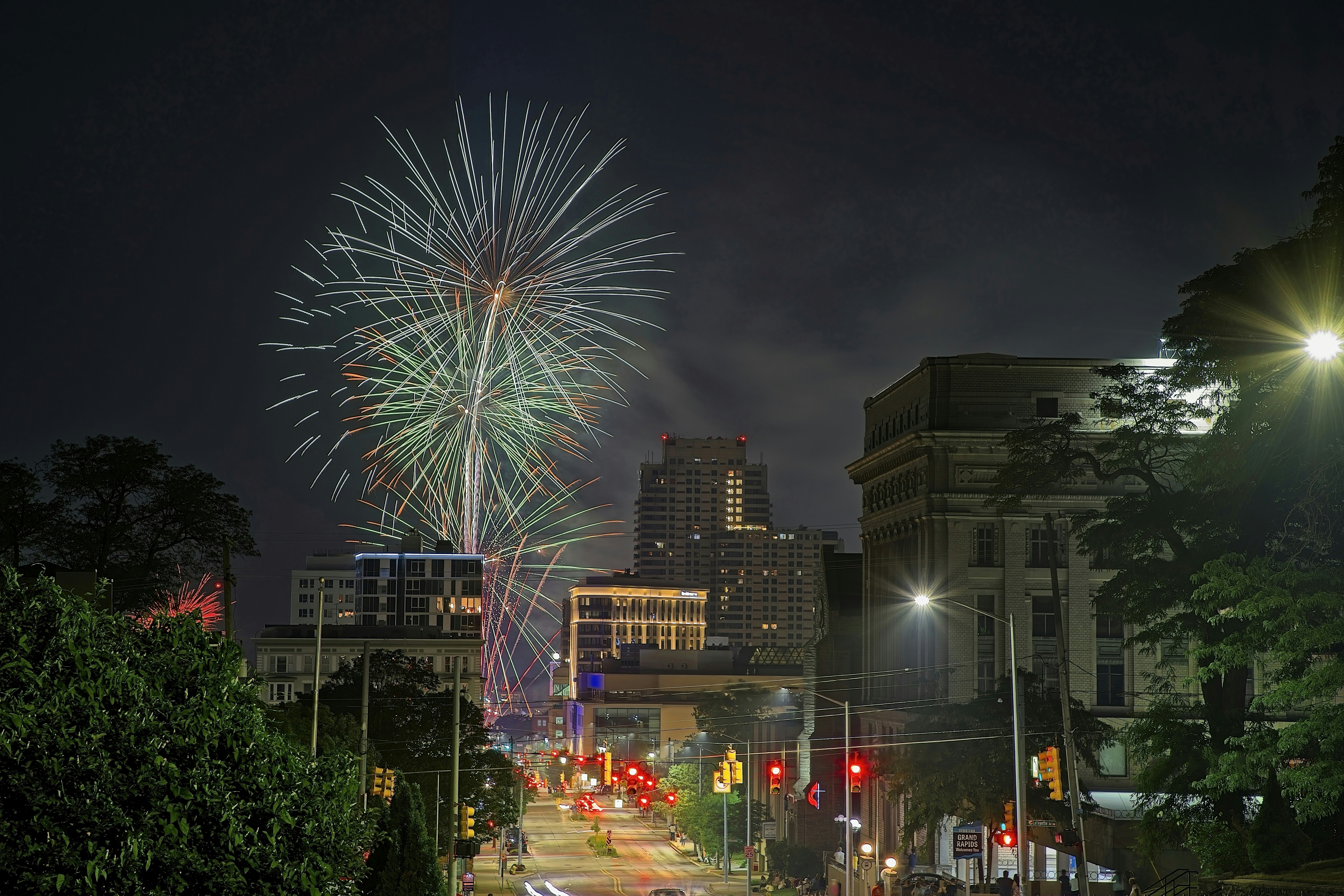 Des feux d’artifice illuminent le ciel nocturne au-dessus d’une rue de la ville.