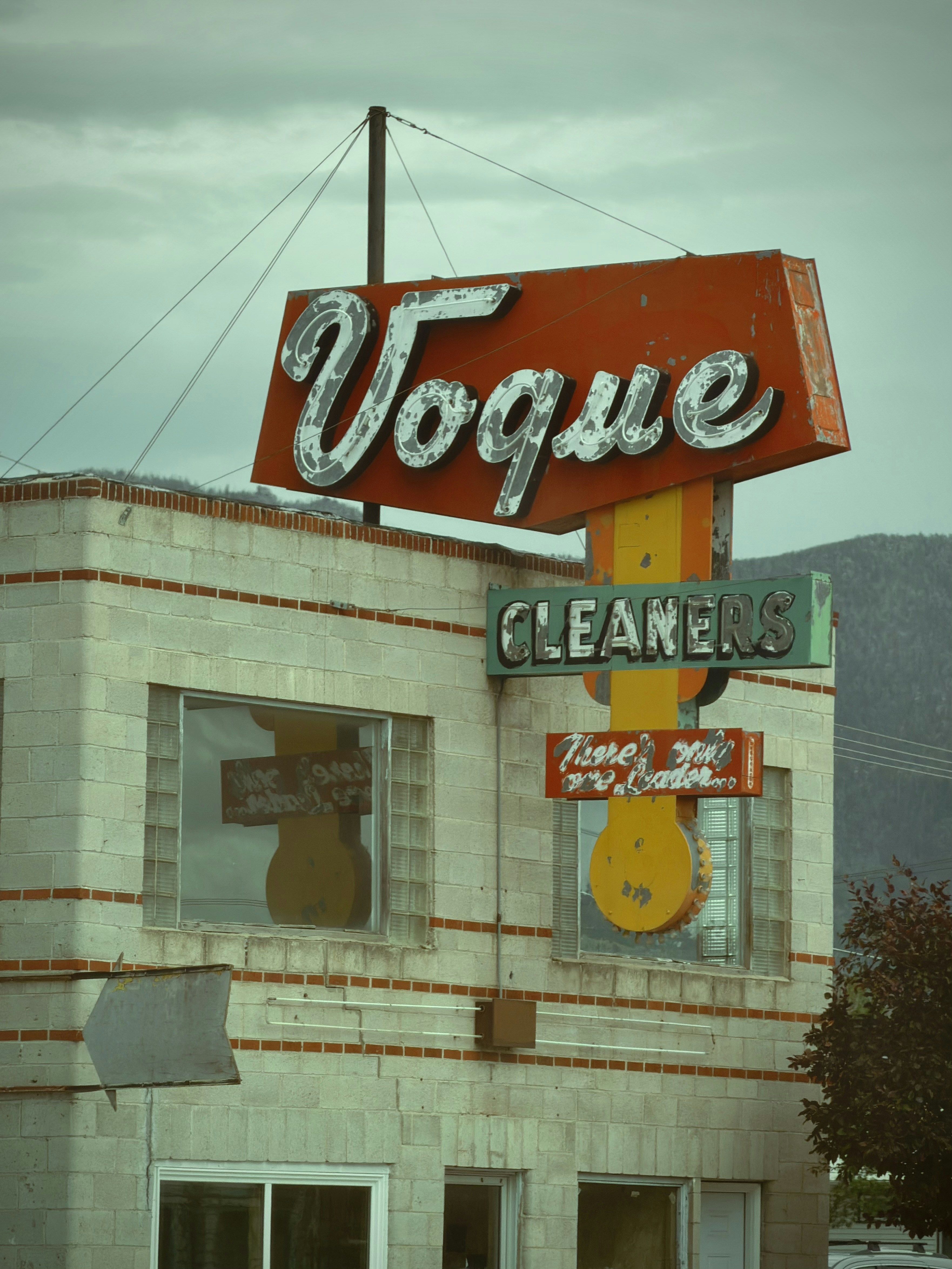 Weathered "vogue cleaners" sign on an old building.