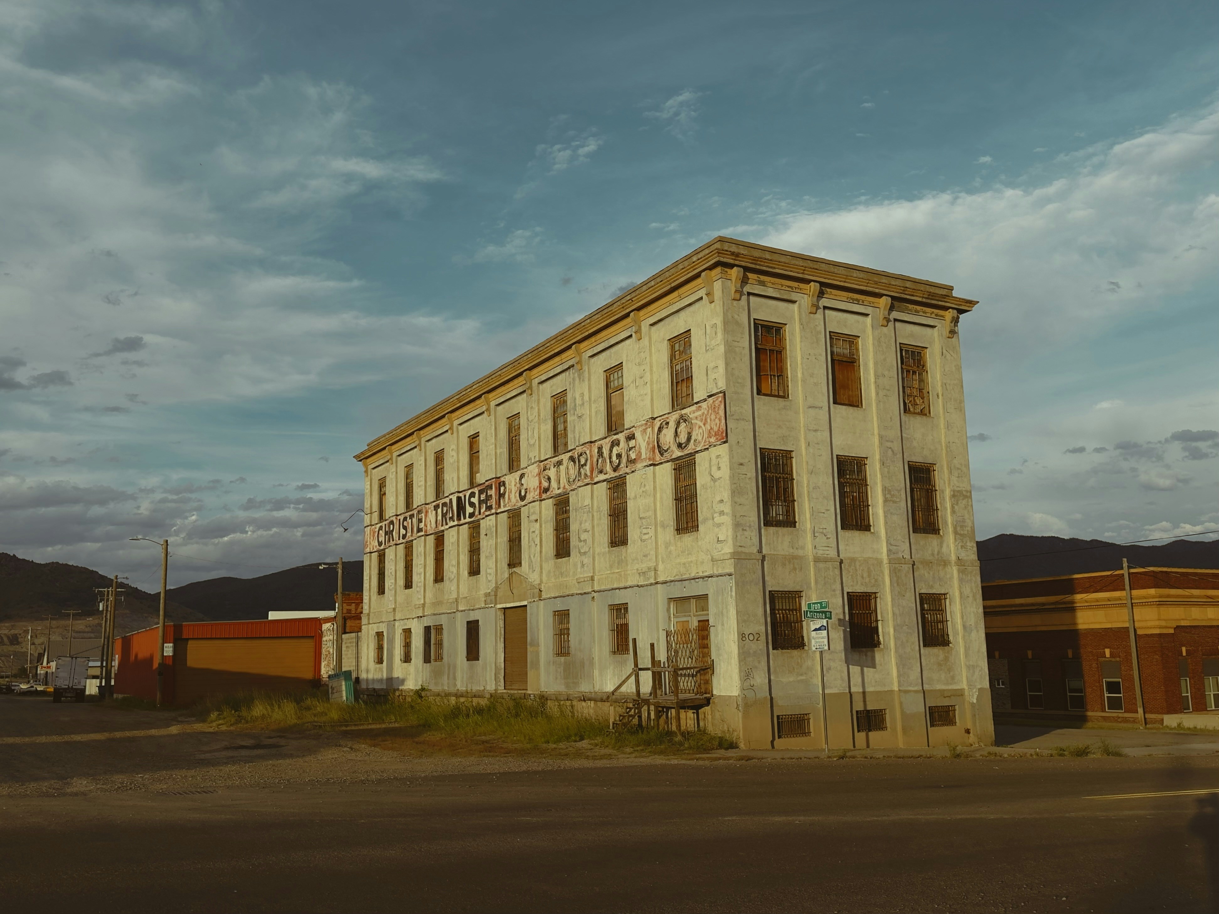 Dilapidated multi-story storage building under a cloudy sky.