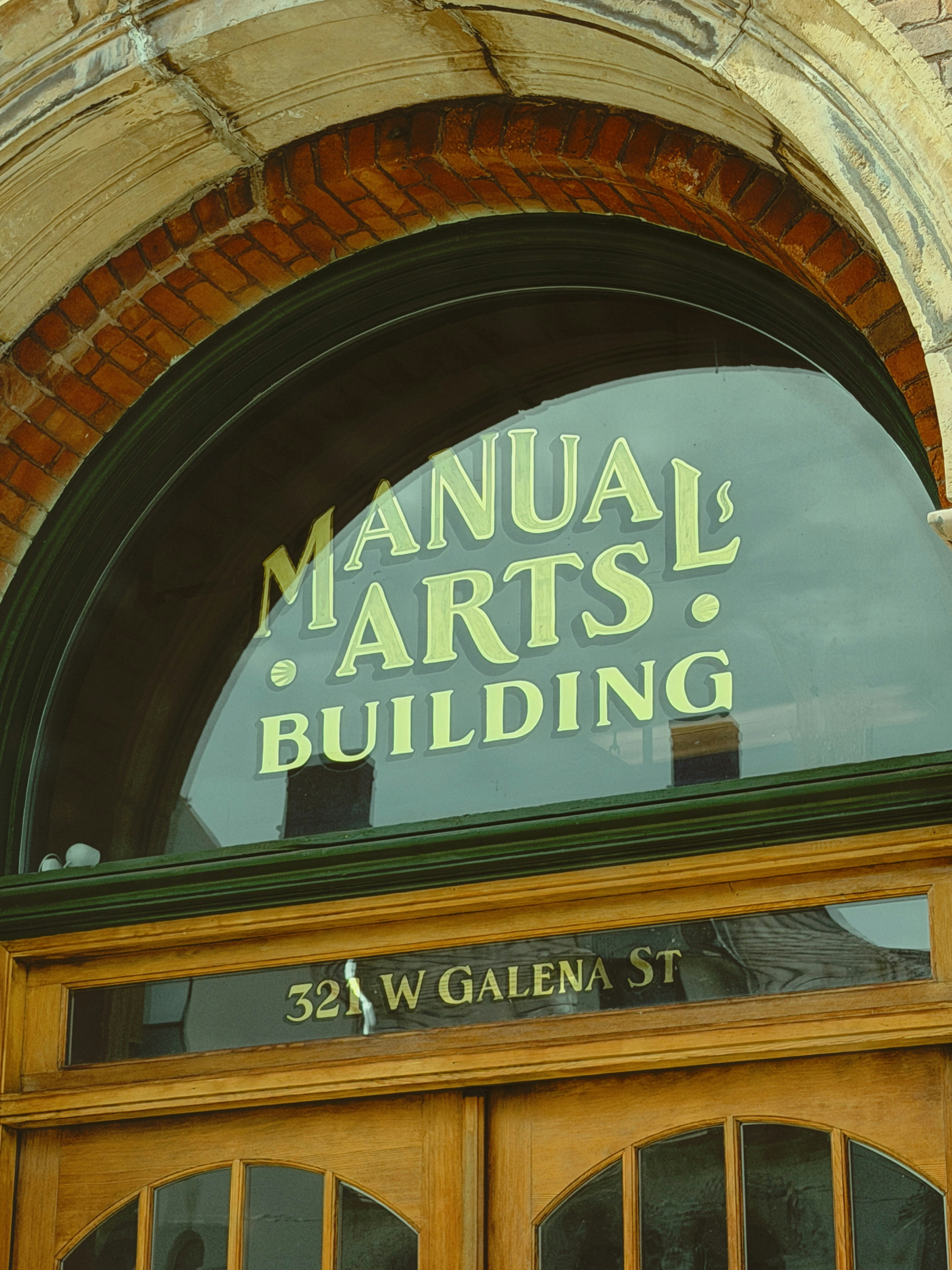 Manual arts building sign above wooden doors.