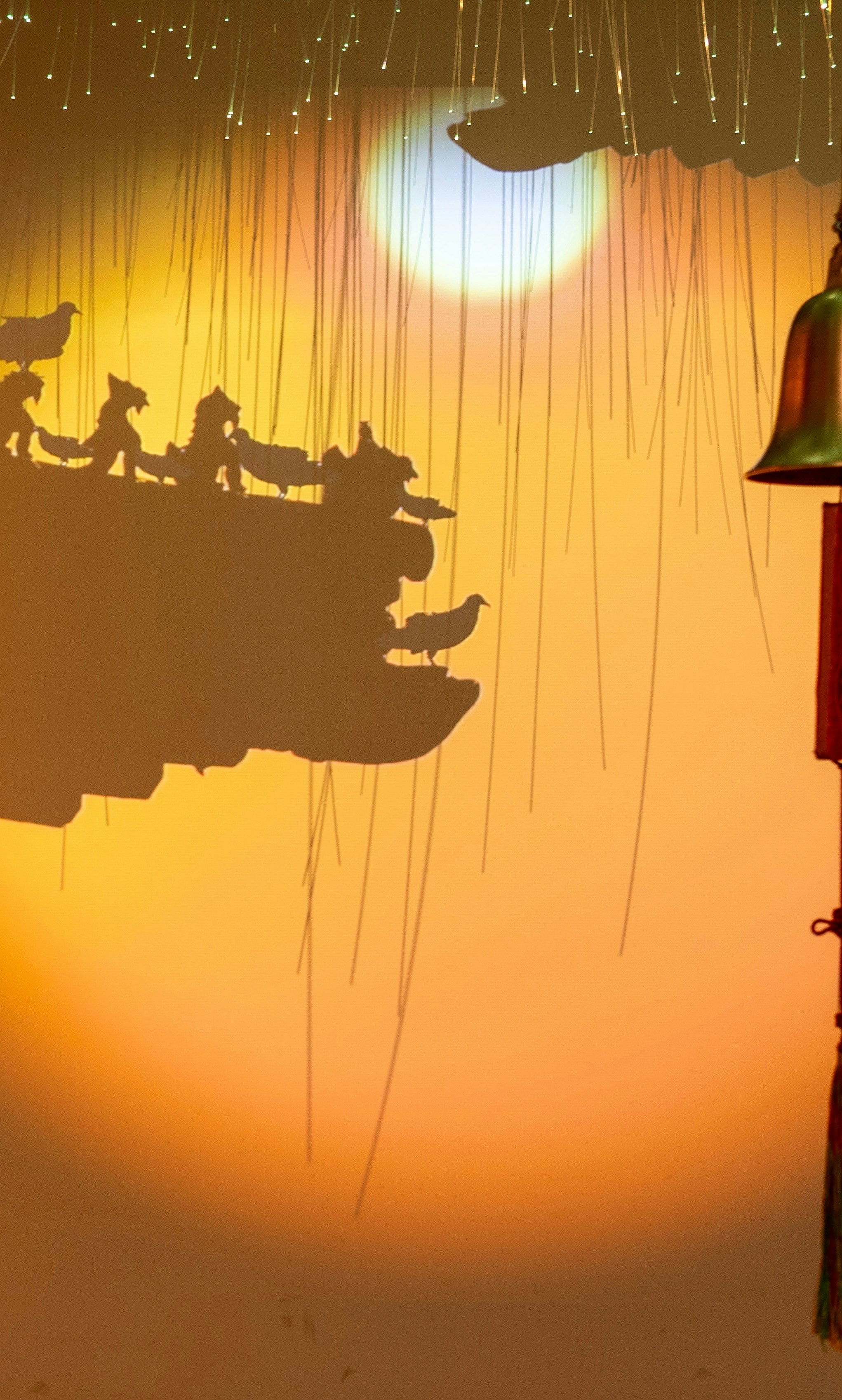 Silhouettes of traditional roof and bell against a glowing sunset
