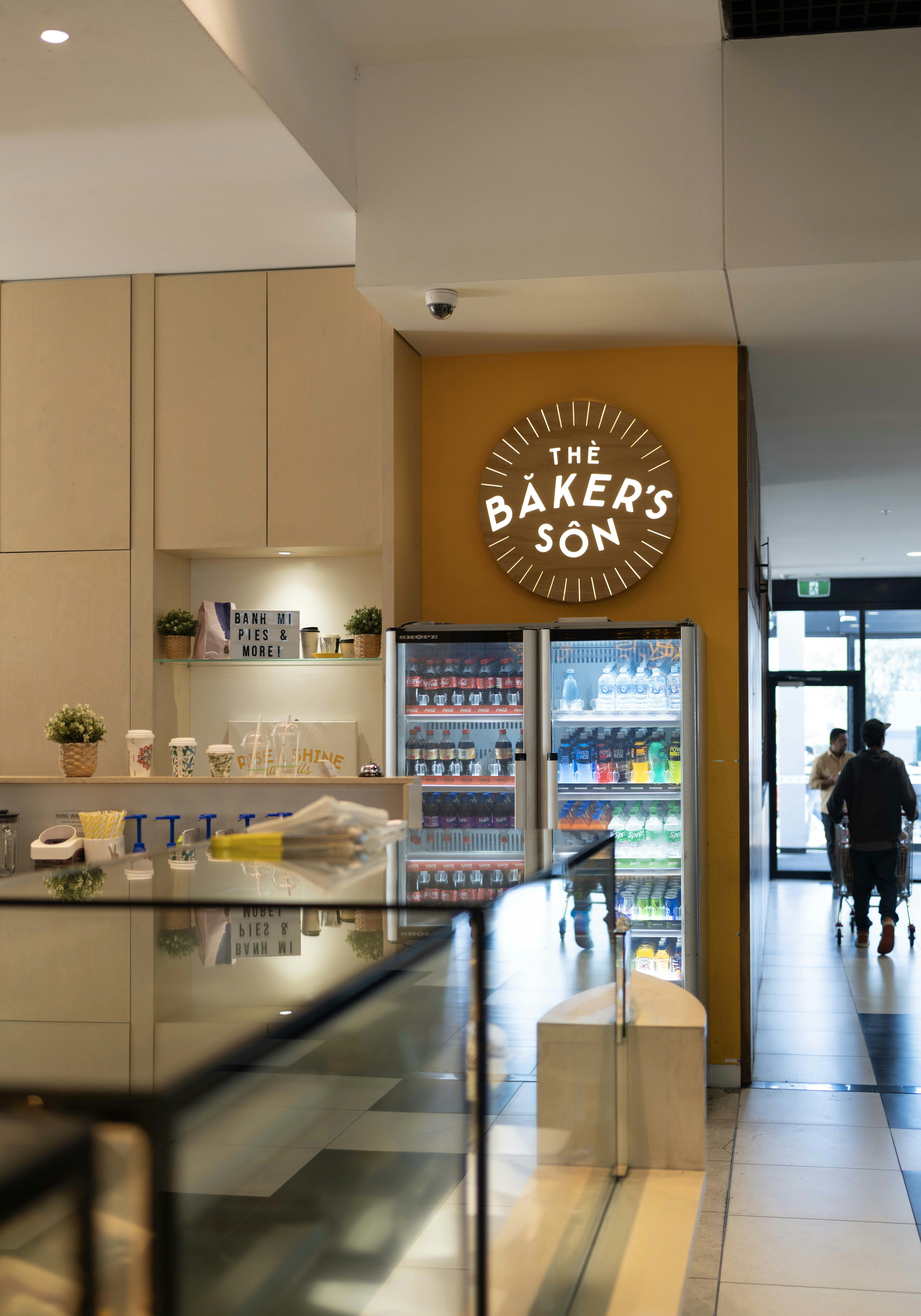 Cafe interior with "the baker's son" sign and beverage refrigerators.