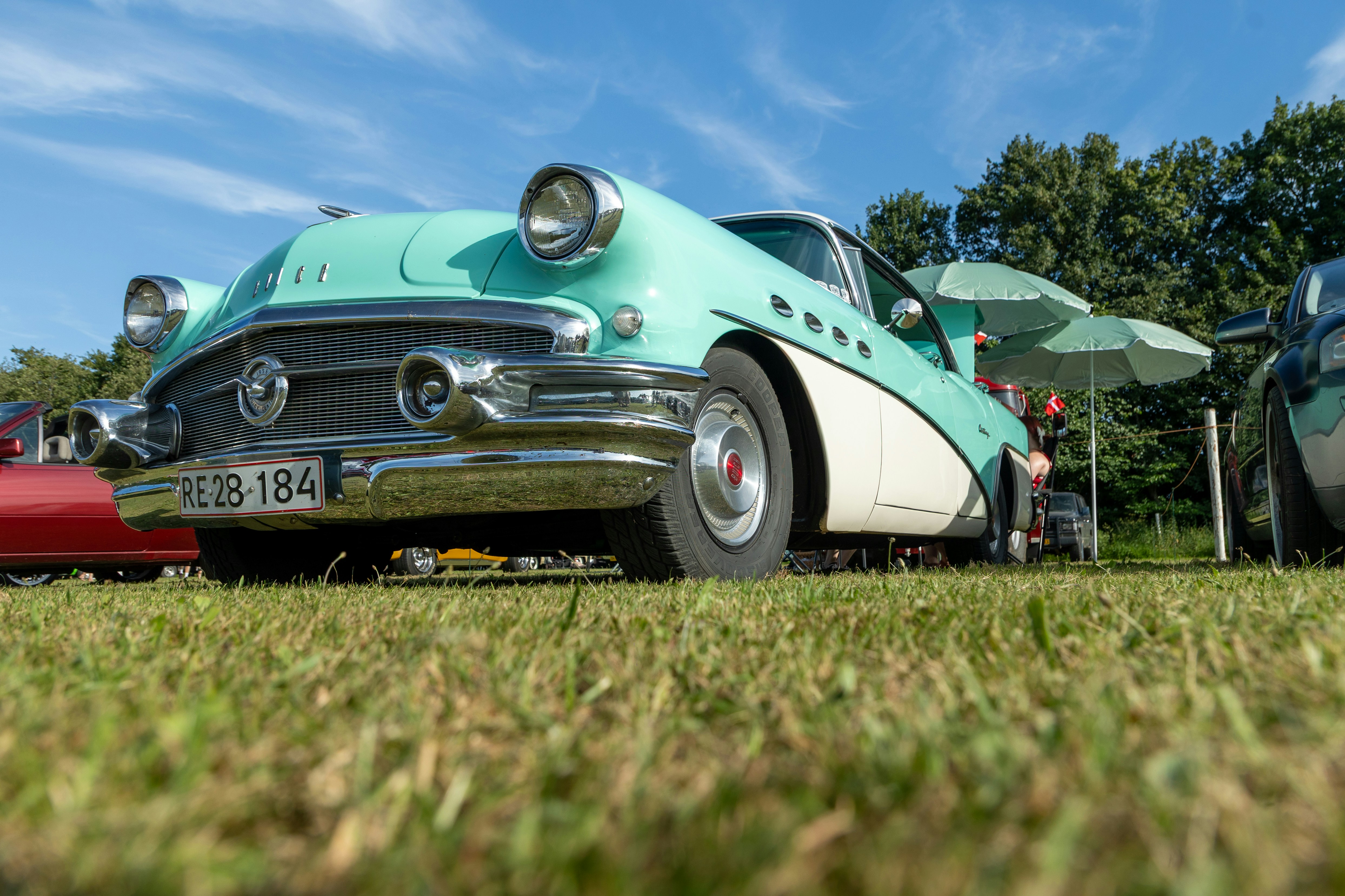 A vintage teal and white car parked on green grass.