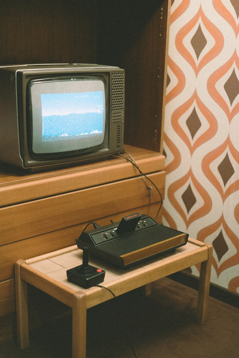A retro TV and vintage game console in front of patterned wallpaper
