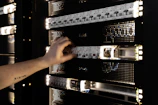 A hand adjusting components in a glowing server rack