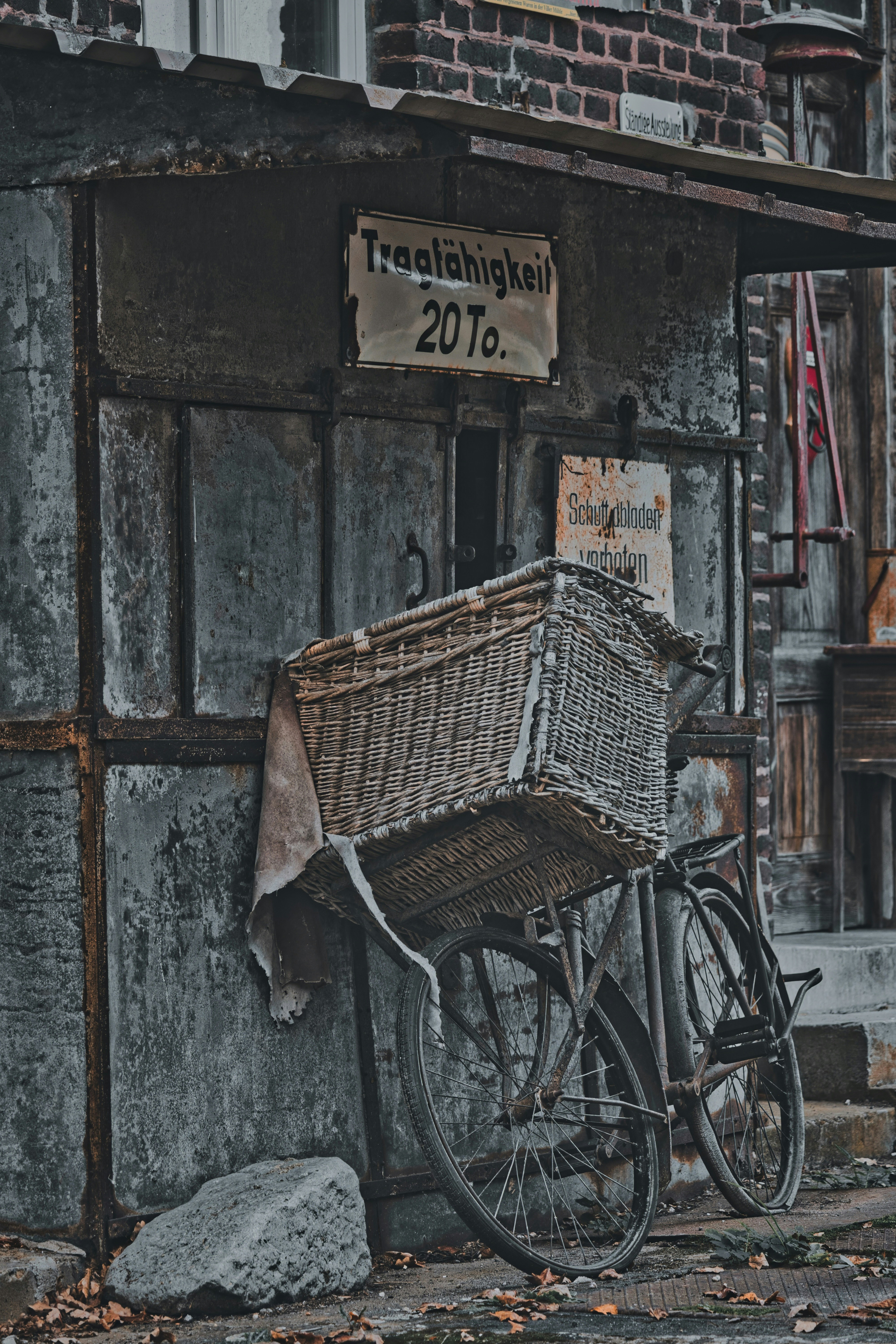 Vintage bicycle with large wicker basket against a weathered building.