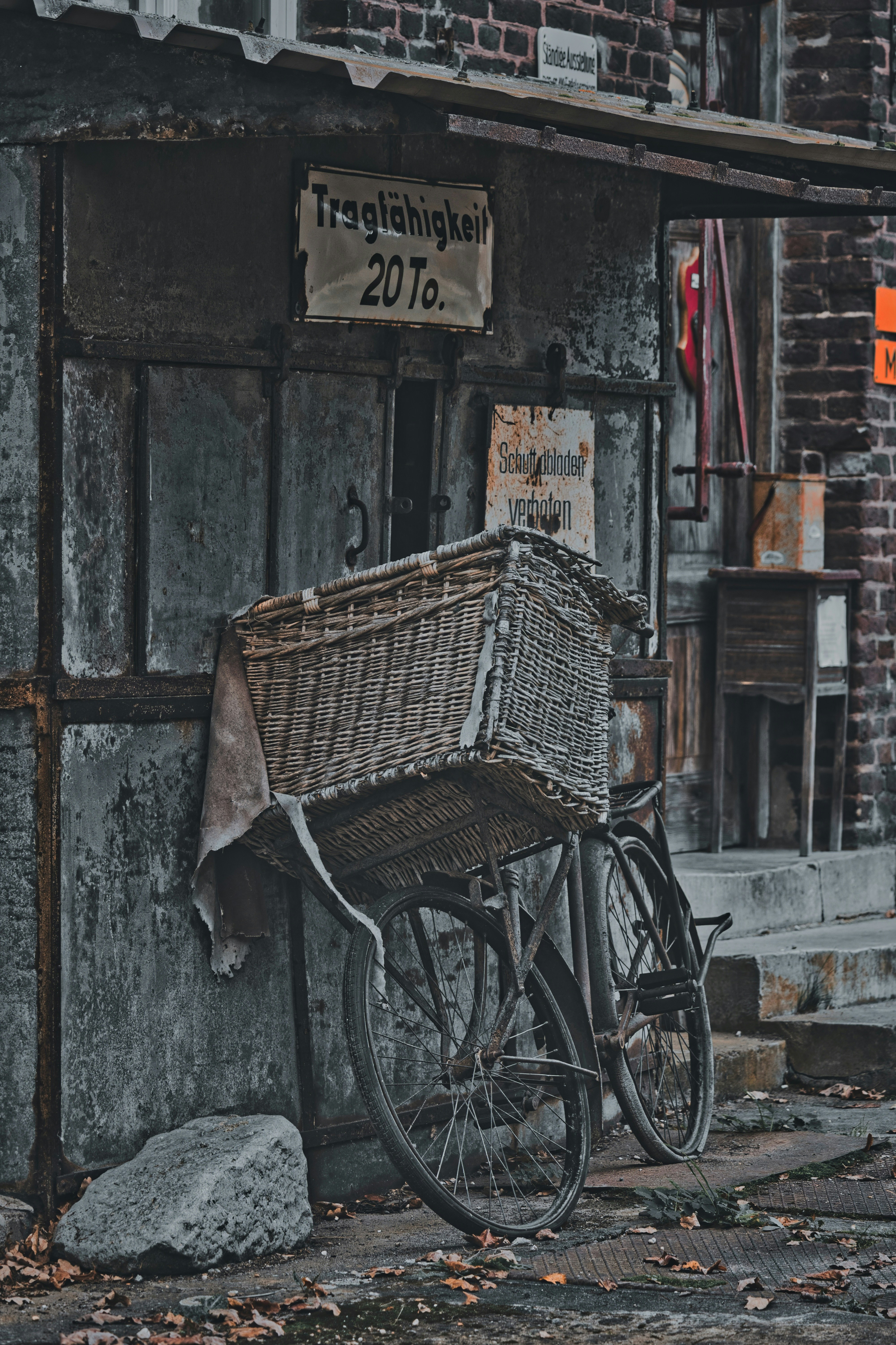 Vintage bicycle with wicker basket leans against an old building.