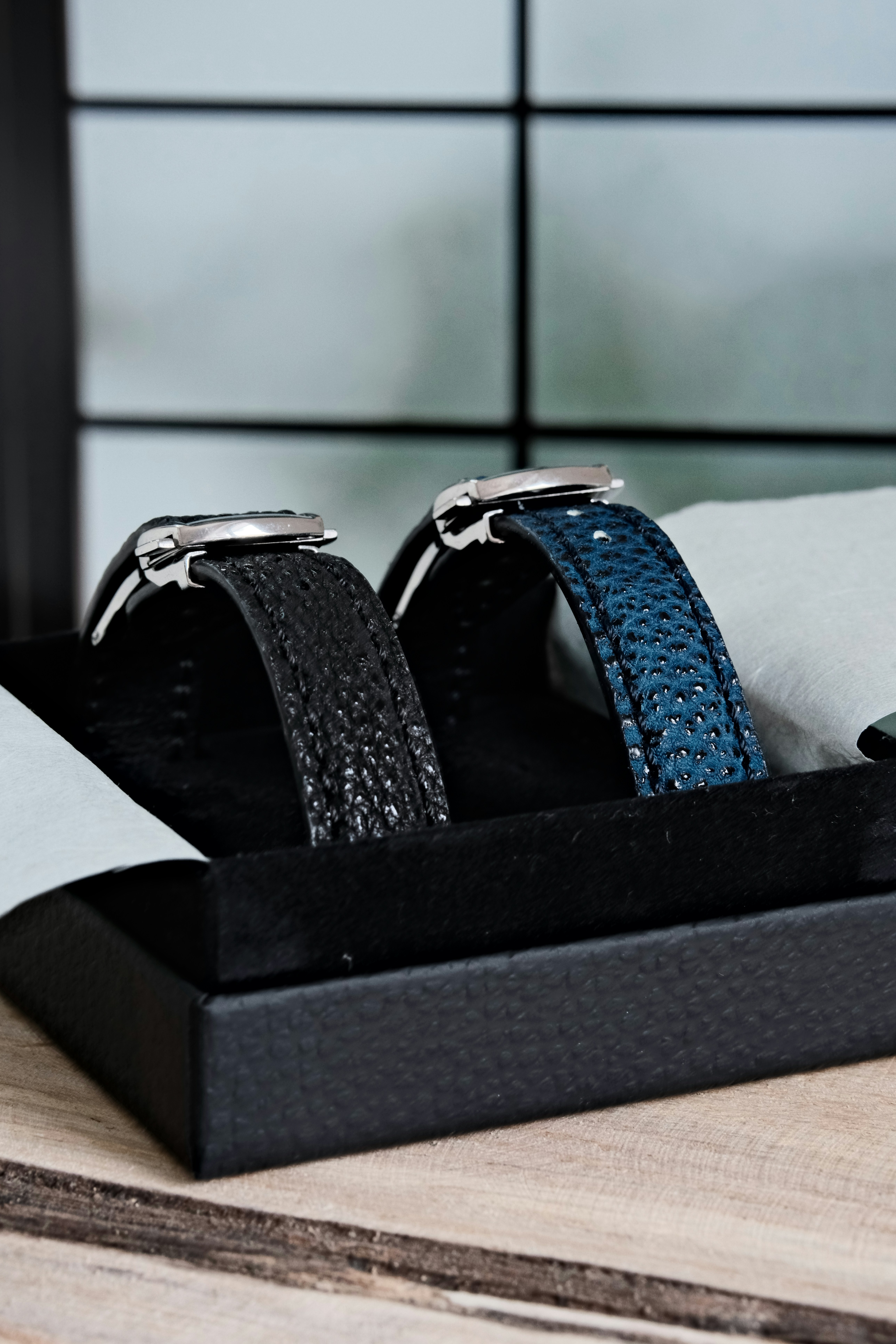 Two luxury watches with textured leather straps in a box.