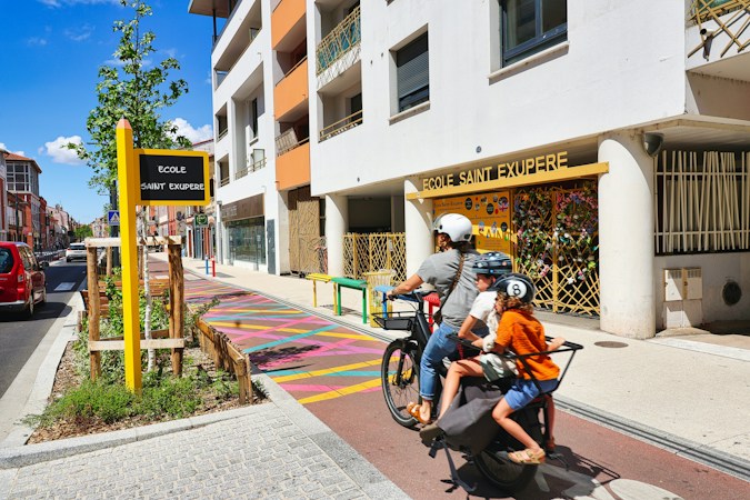 Family riding bikes together on an urban bike path, showing why drivers need to watch for cyclists near schools