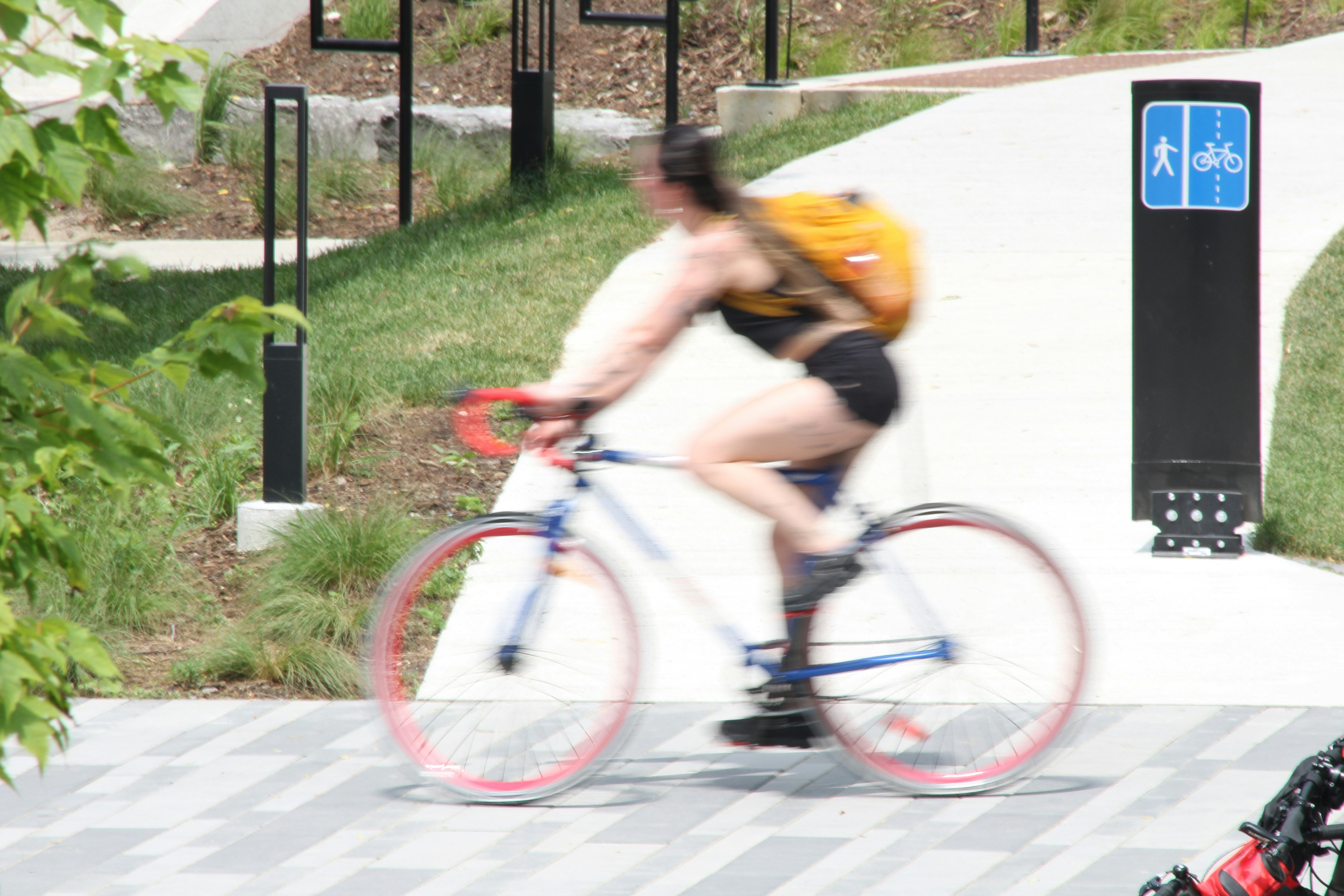 Woman with backpack rides bicycle on a paved path