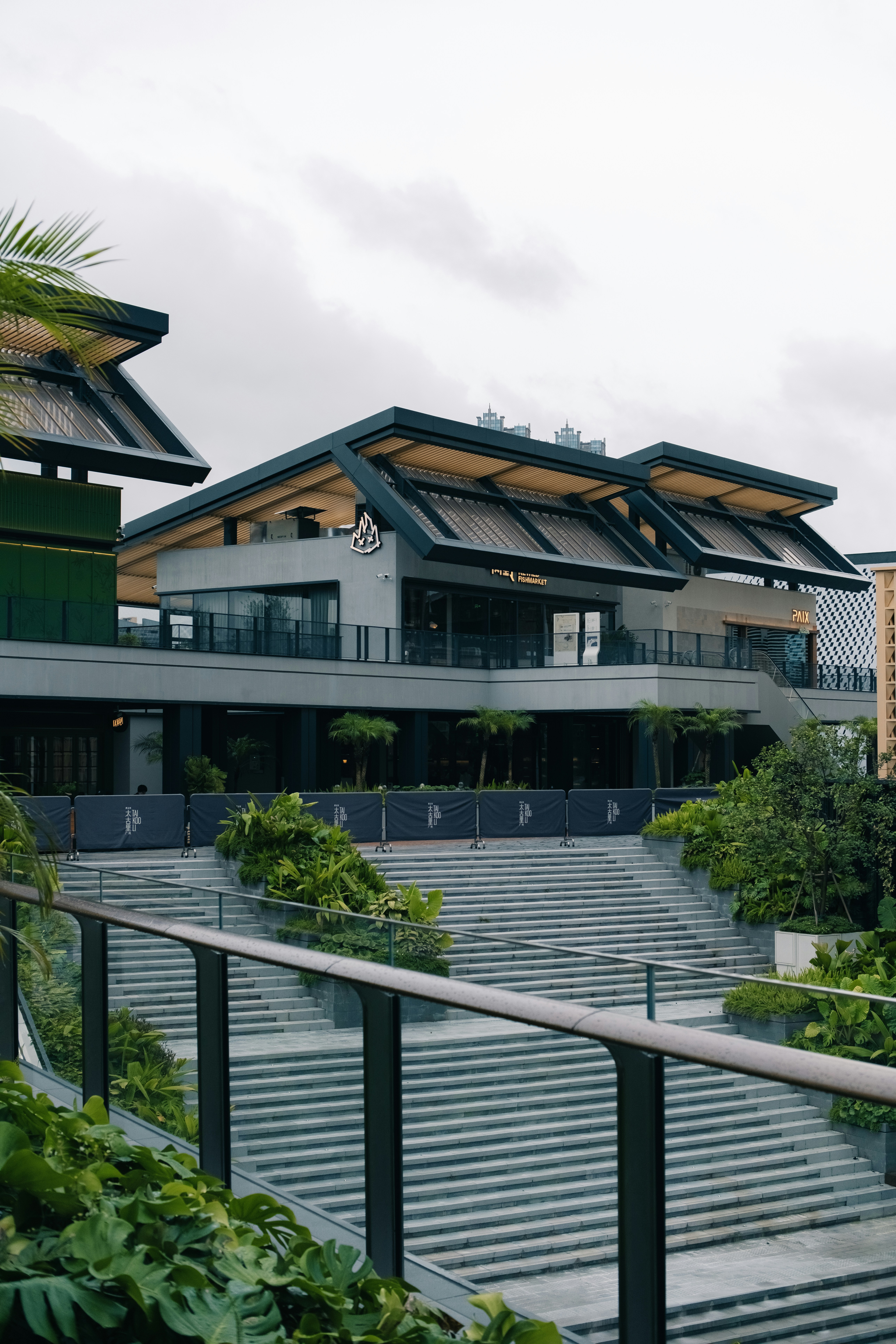 Modern building with wide stairs and lush green plants.