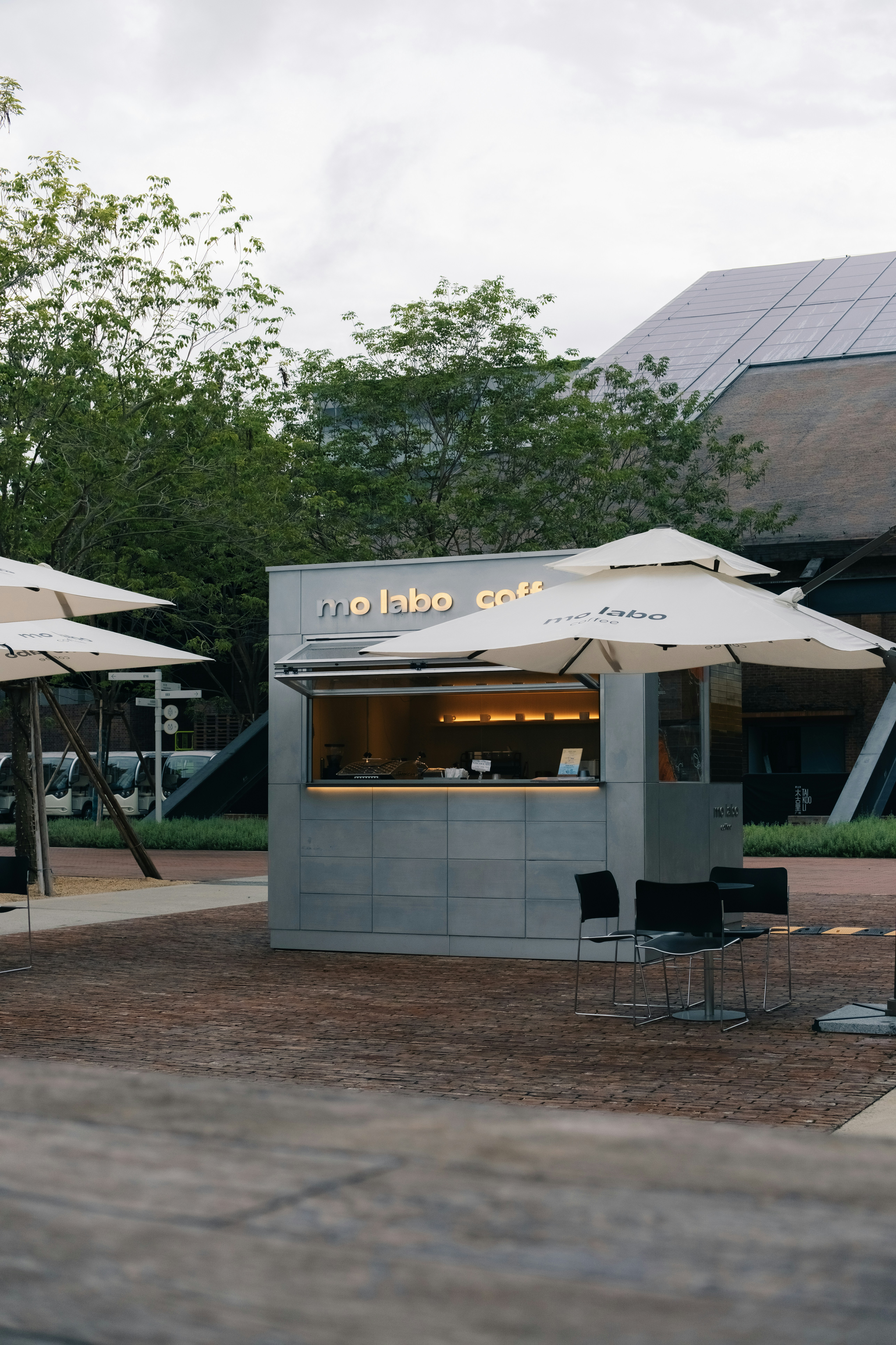 A modern coffee stand named 'mo inbo coffee' with umbrellas.