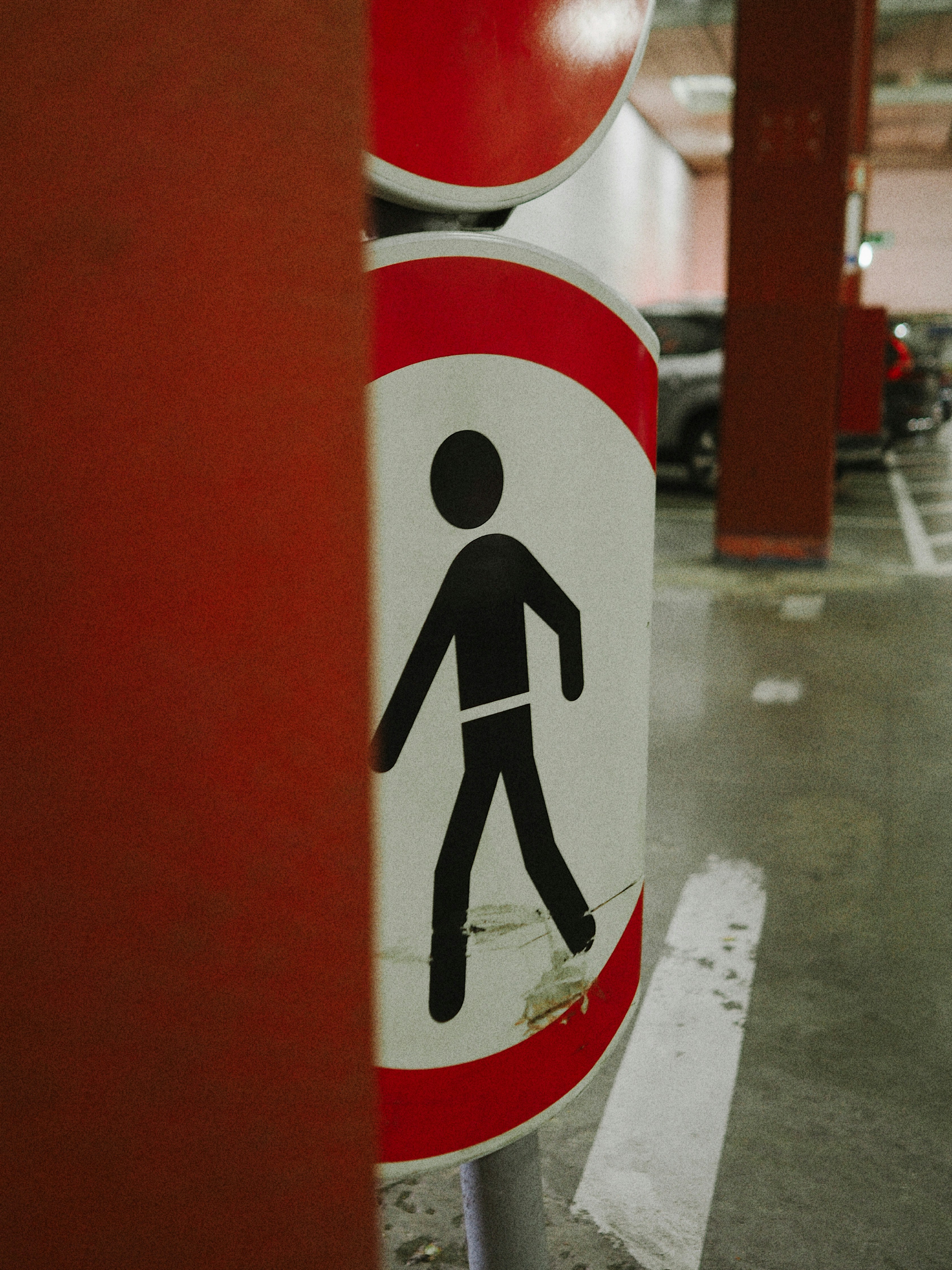 A 'no pedestrian' sign partially hidden in a parking garage.