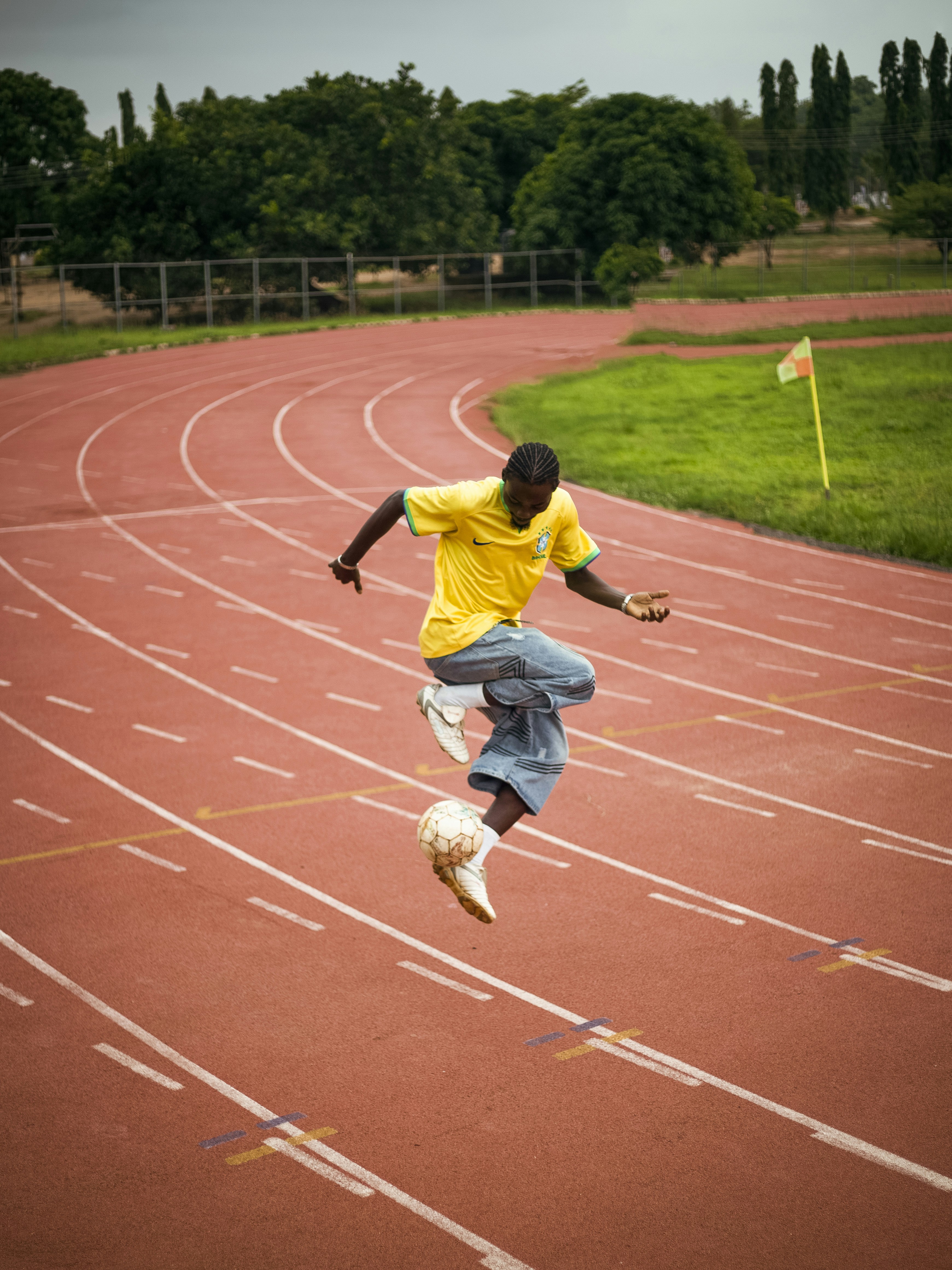 Soccer player juggling ball mid-air on a red running track - Free Photo ...