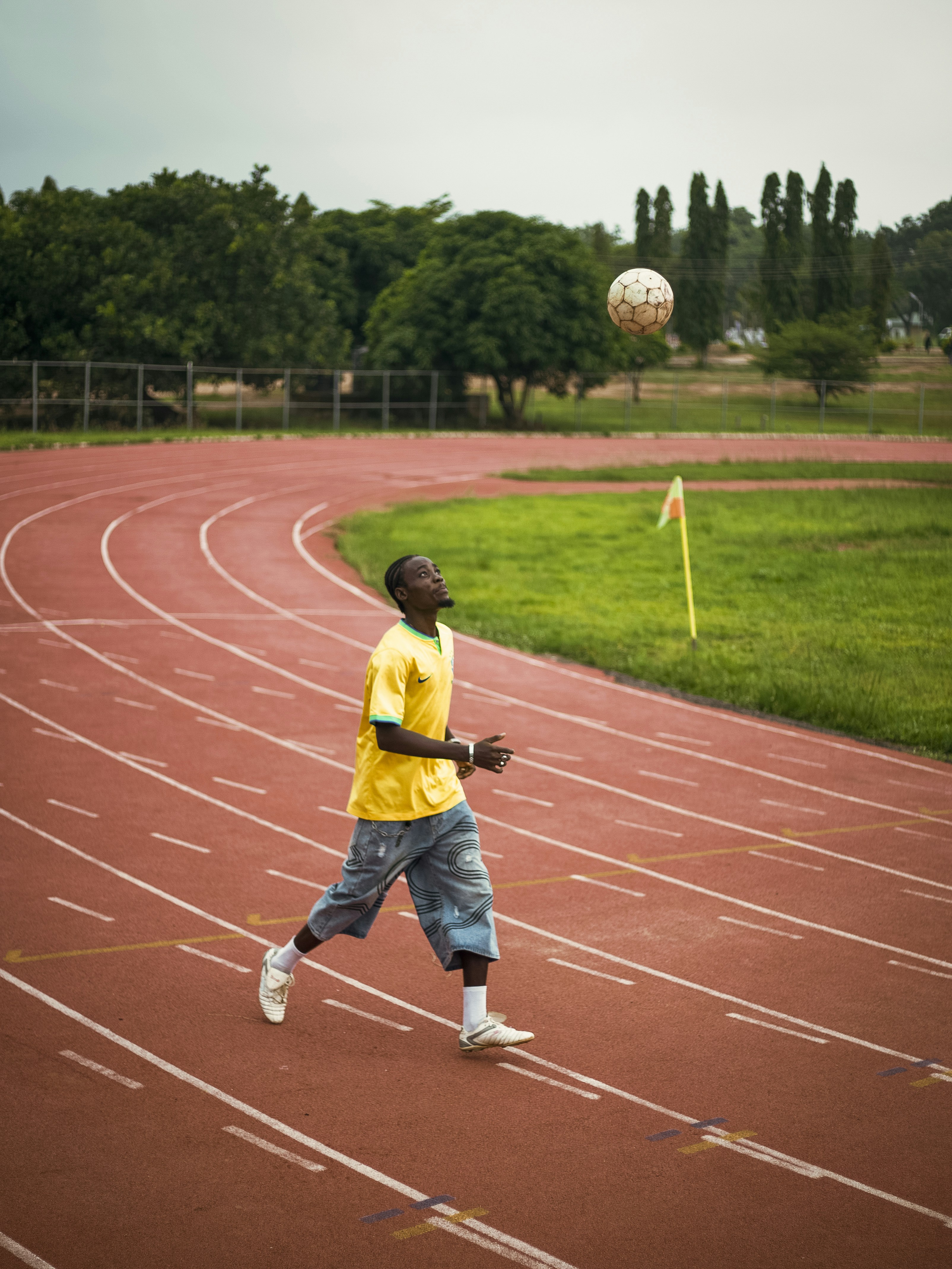 Young man heading soccer ball on a running track