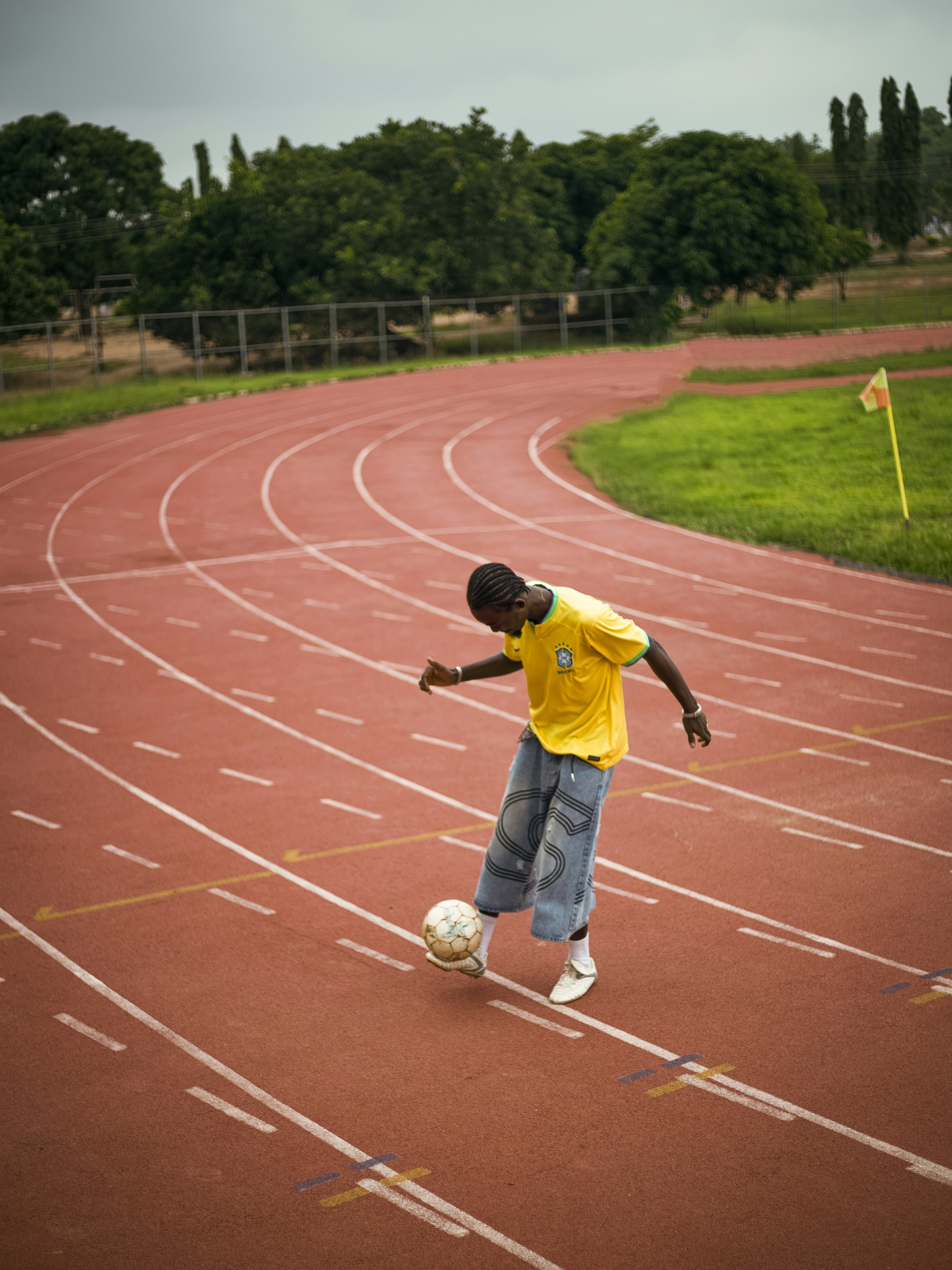 Young boy juggling a soccer ball on a running track