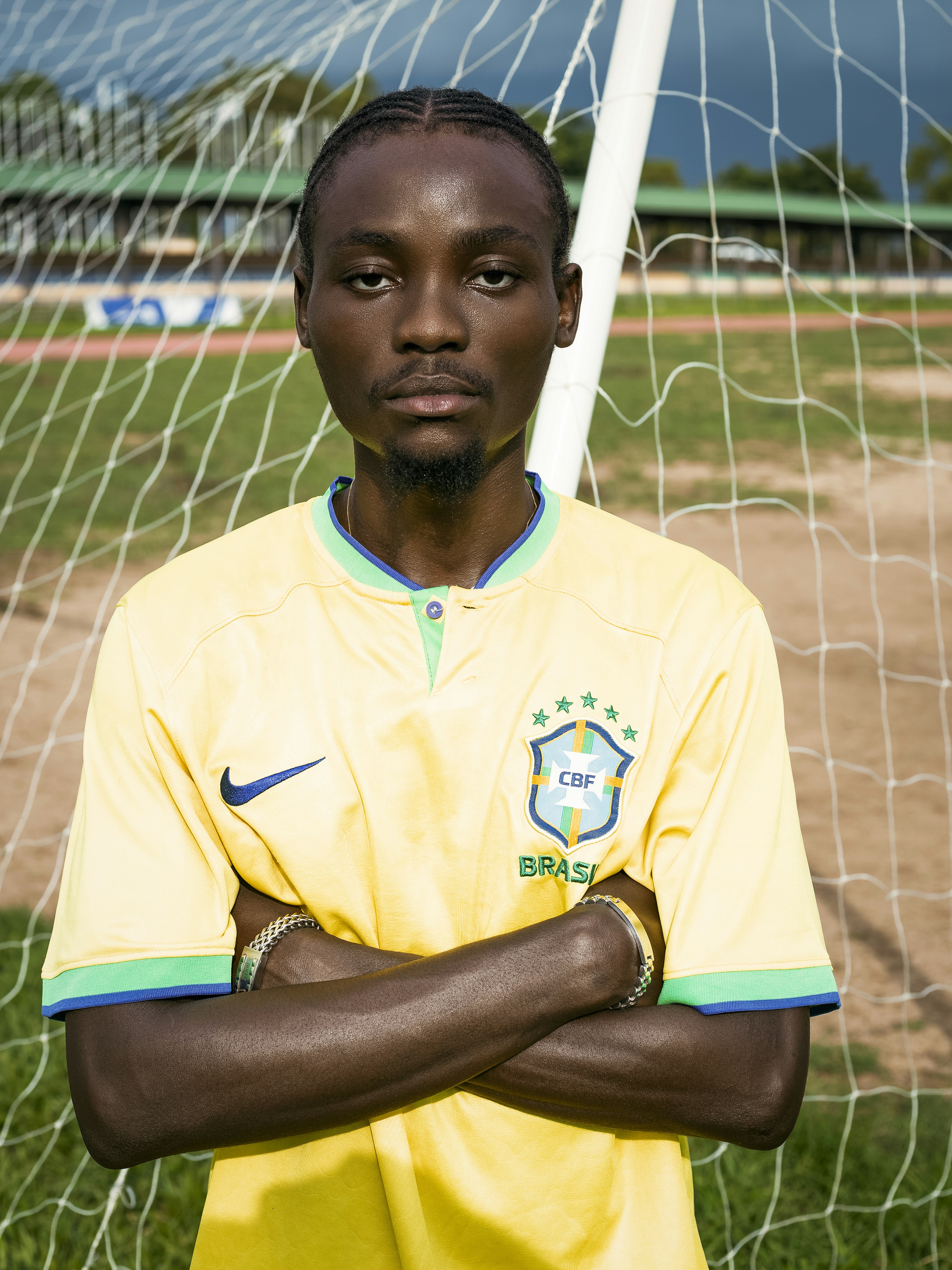 Man in yellow brazil jersey posing by a soccer goal